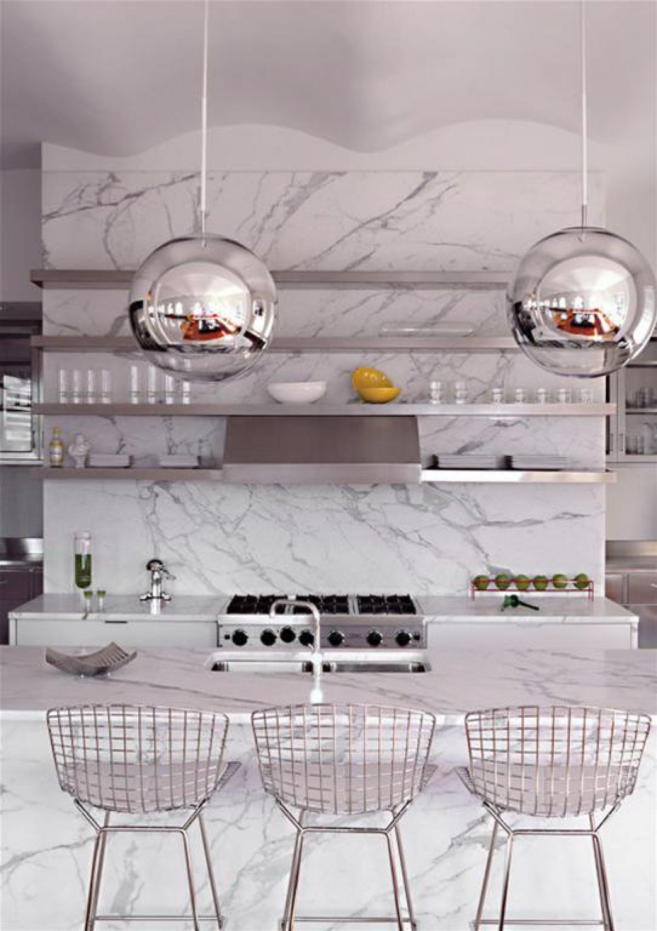 Drei Bertoia Barhocker von Knoll International in einer modernen Küche mit Marmor-Arbeitsplatte und Pendelleuchten.