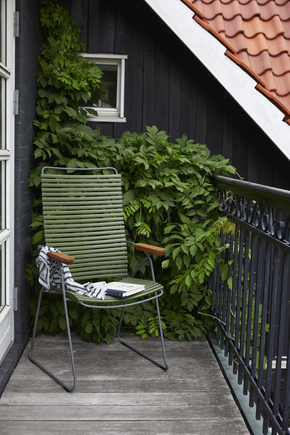 Grüner Click Position Chair von Houe auf Balkon mit Buch und Handtuch. Outdoor Sessel.