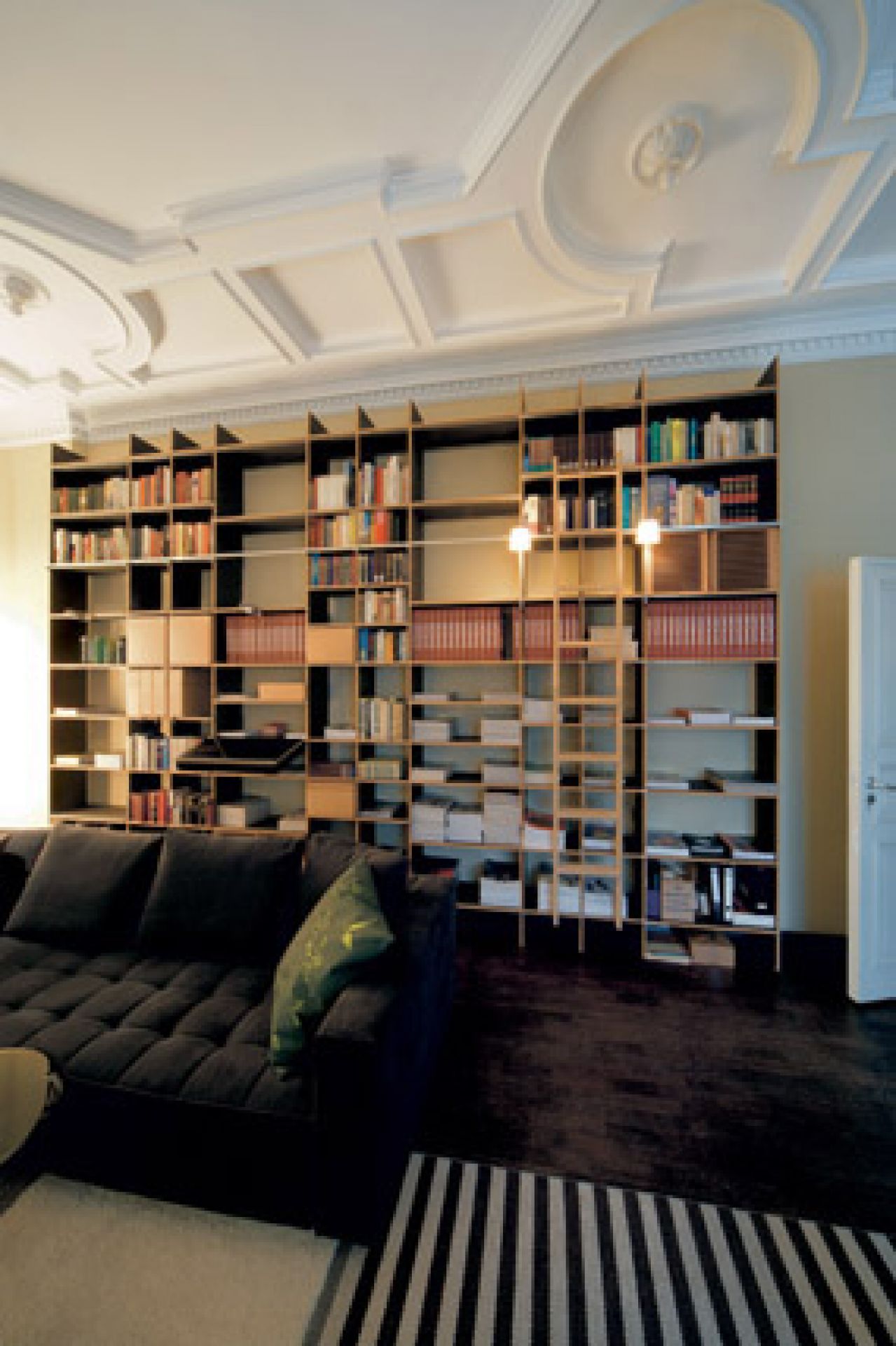 Wohnzimmer mit großem FNP Regal von Moormann, gefüllt mit Büchern und Dekoration.