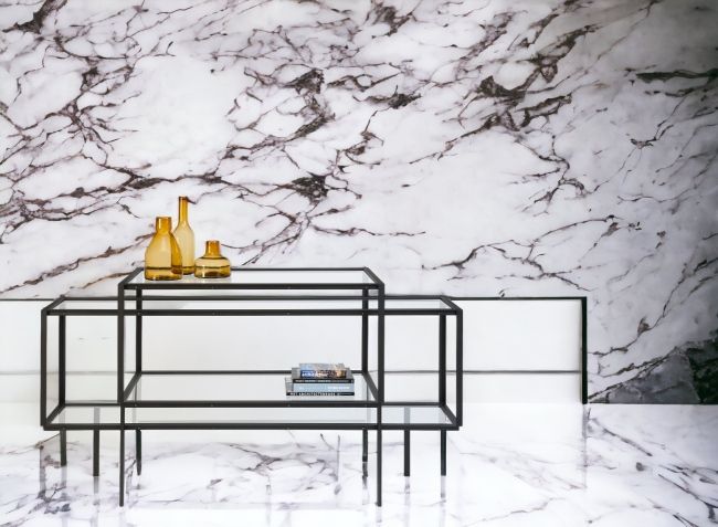 Tangled Kabinettschrank Sideboard Spectrum mit Glasablagen und schwarzem Metallgestell vor Marmorwand.