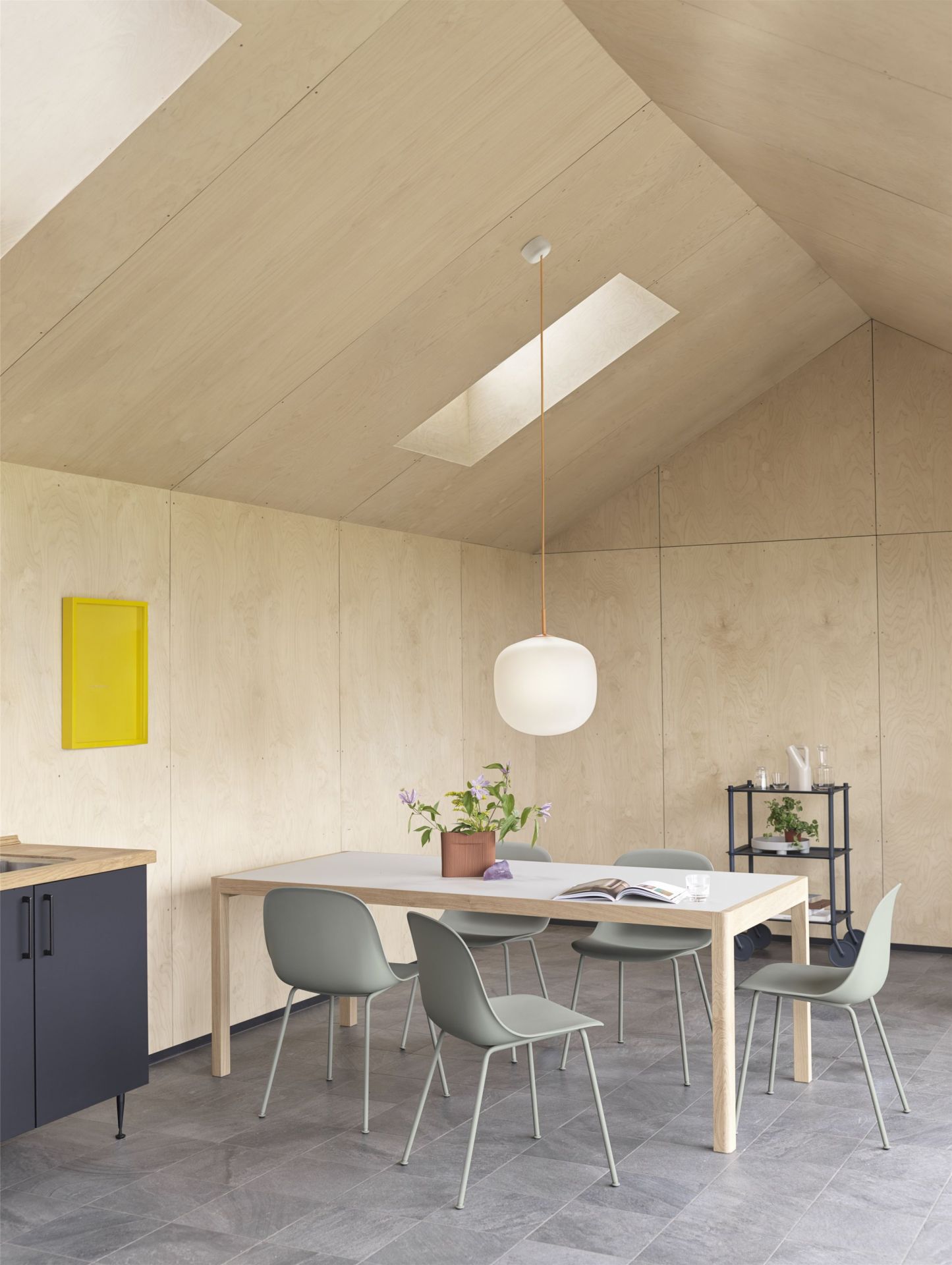 Helle Küche mit Esstisch und vier grauen Muuto Fiber Side Chairs mit Stahlrohrgestell.