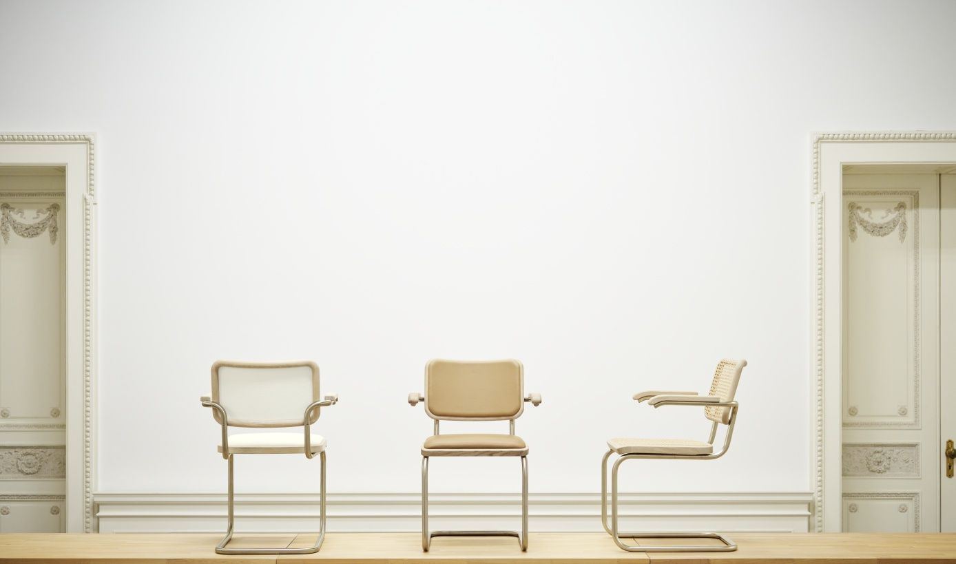 Drei JS. Thonet Freischwinger S 64 P Stühle in Beige, Weiß und Rattan vor weißer Wand und Türen.