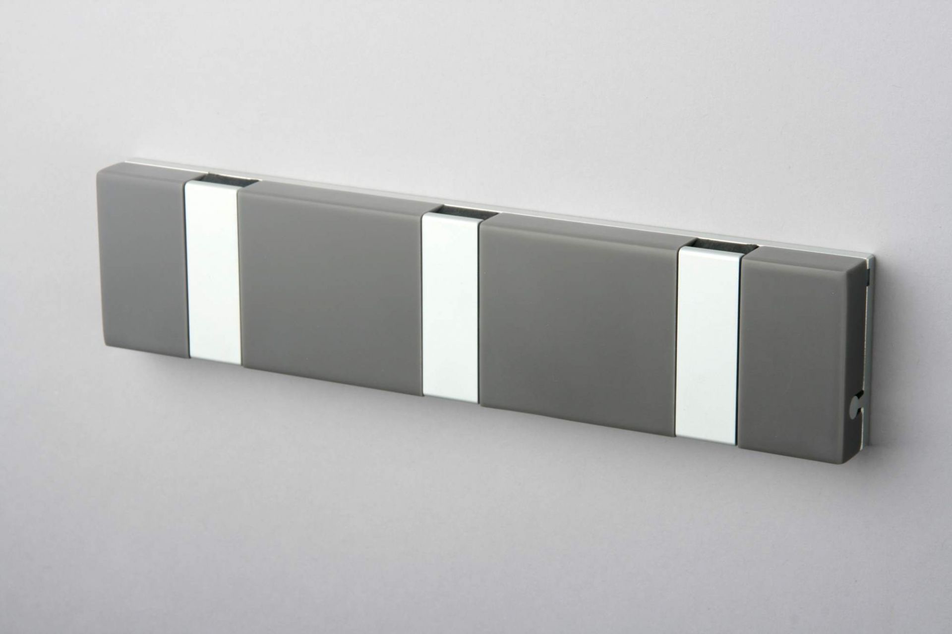 Graue Knax Lite Wandgarderobe mit drei Haken, waagerecht an einer Wand montiert. Moderne Garderobenleiste.