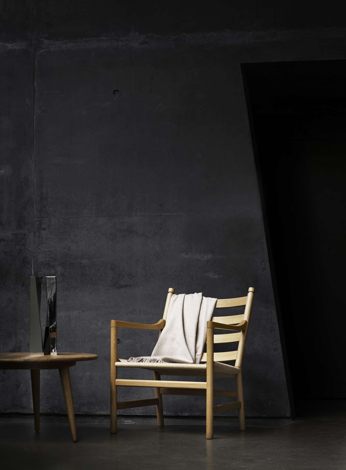 CH008 Couchtisch aus Eiche von Carl Hansen & Søn neben einem Holzstuhl mit Decke.