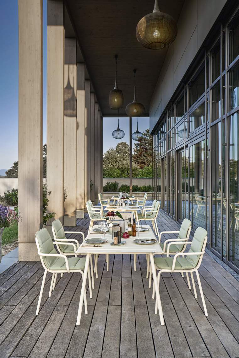 Vapio Sessel Outdoor Weishäupl: Elegante Gartenmöbel, weiße Sessel mit grünen Polstern an gedeckten Tischen auf Terrasse.