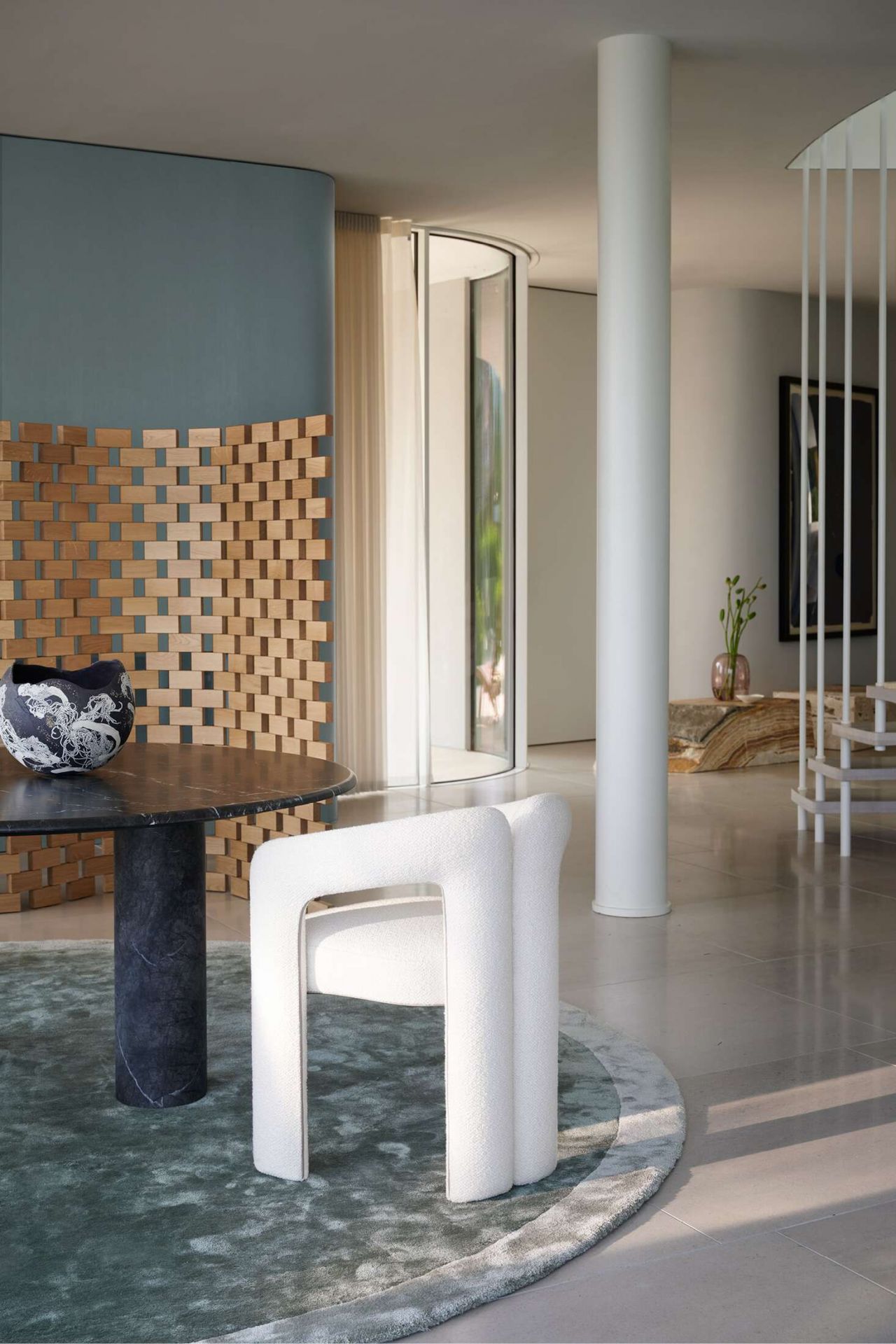 Weißer Cassina 562 Dudet Sessel mit Bouclé-Bezug in modernem Interieur, kombiniert mit Marmortisch und Teppich.