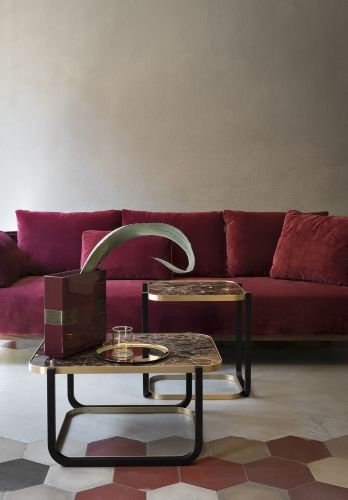 Duet B Couchtisch von Wiener GTV Design mit Marmorplatte und schwarzem Metallgestell vor rotem Sofa.