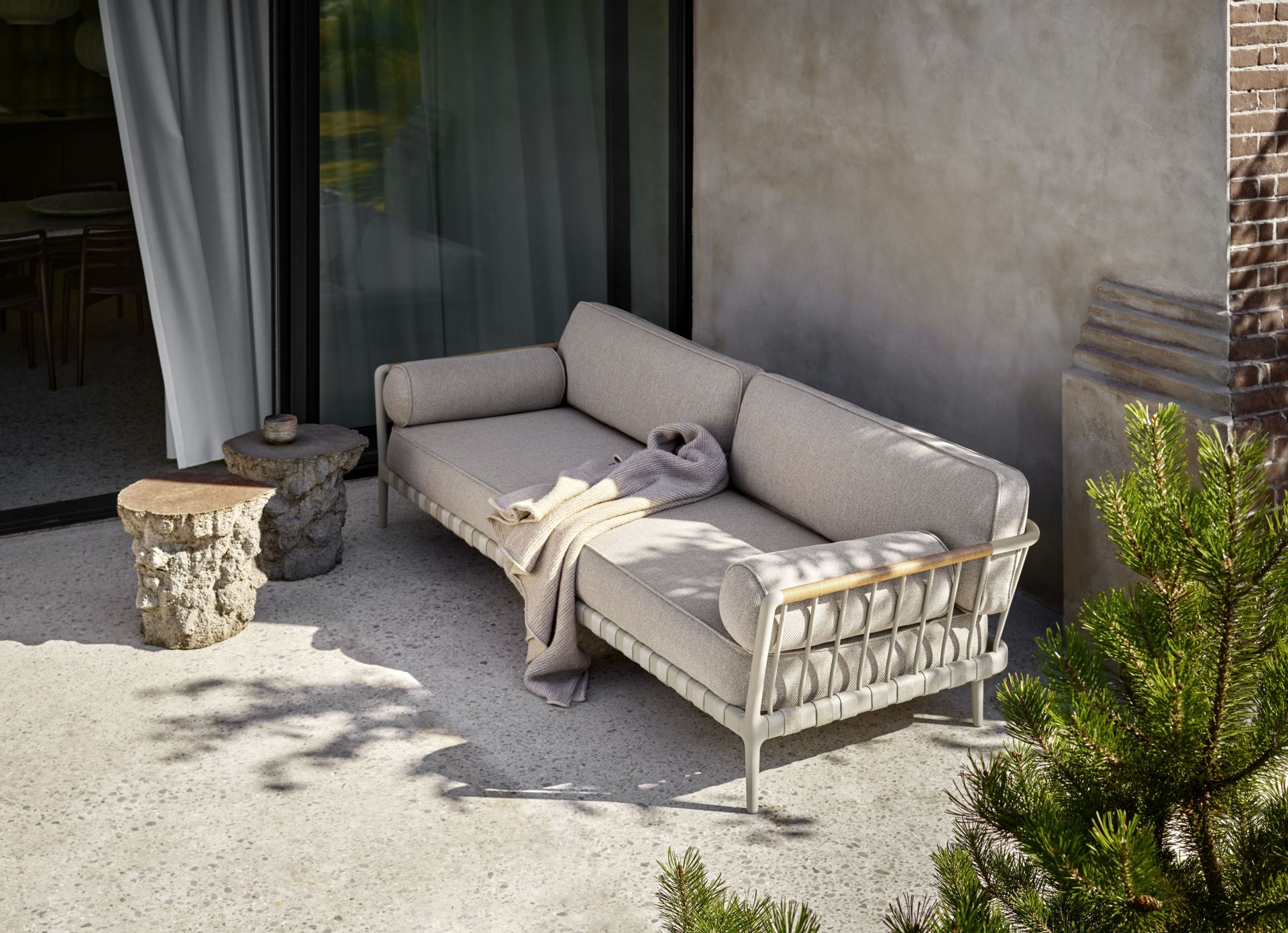 Open-Air Vipp 3-Sitzer Outdoor Sofa mit hellgrauem Bezug und passender Decke im Garten.