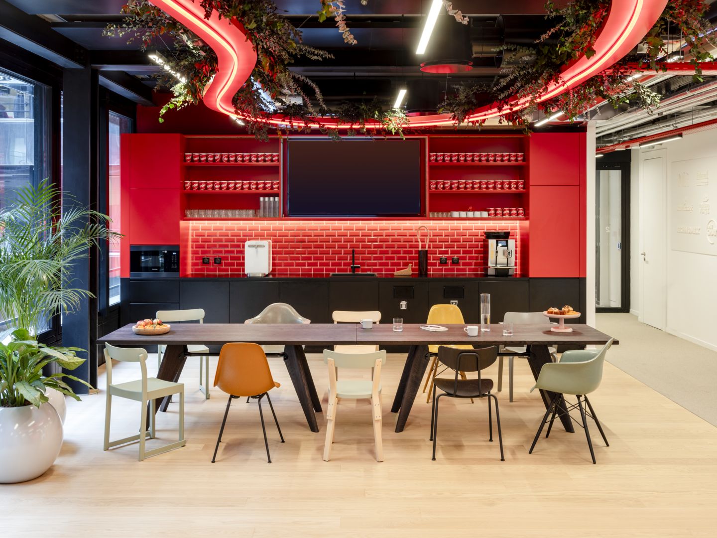 Esstisch mit verschiedenen Eames Fiberglass Stühlen DSX von Vitra und Sitzpolster in modernem Büro.