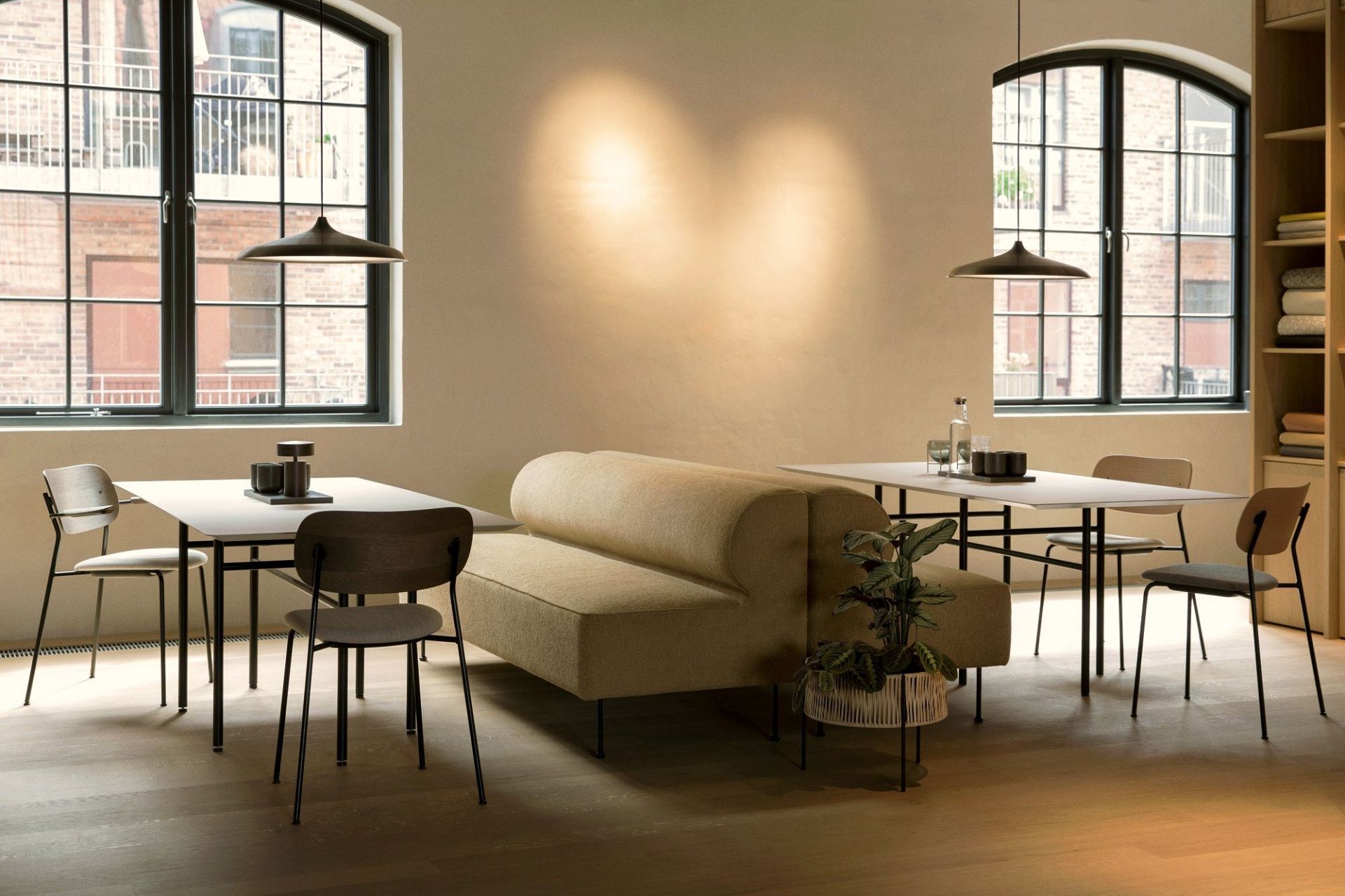 Esszimmer Interieur mit zwei Esstischen, Sofa und Audo Copenhagen Co Dining Chair Stühlen mit schwarzen Beinen.