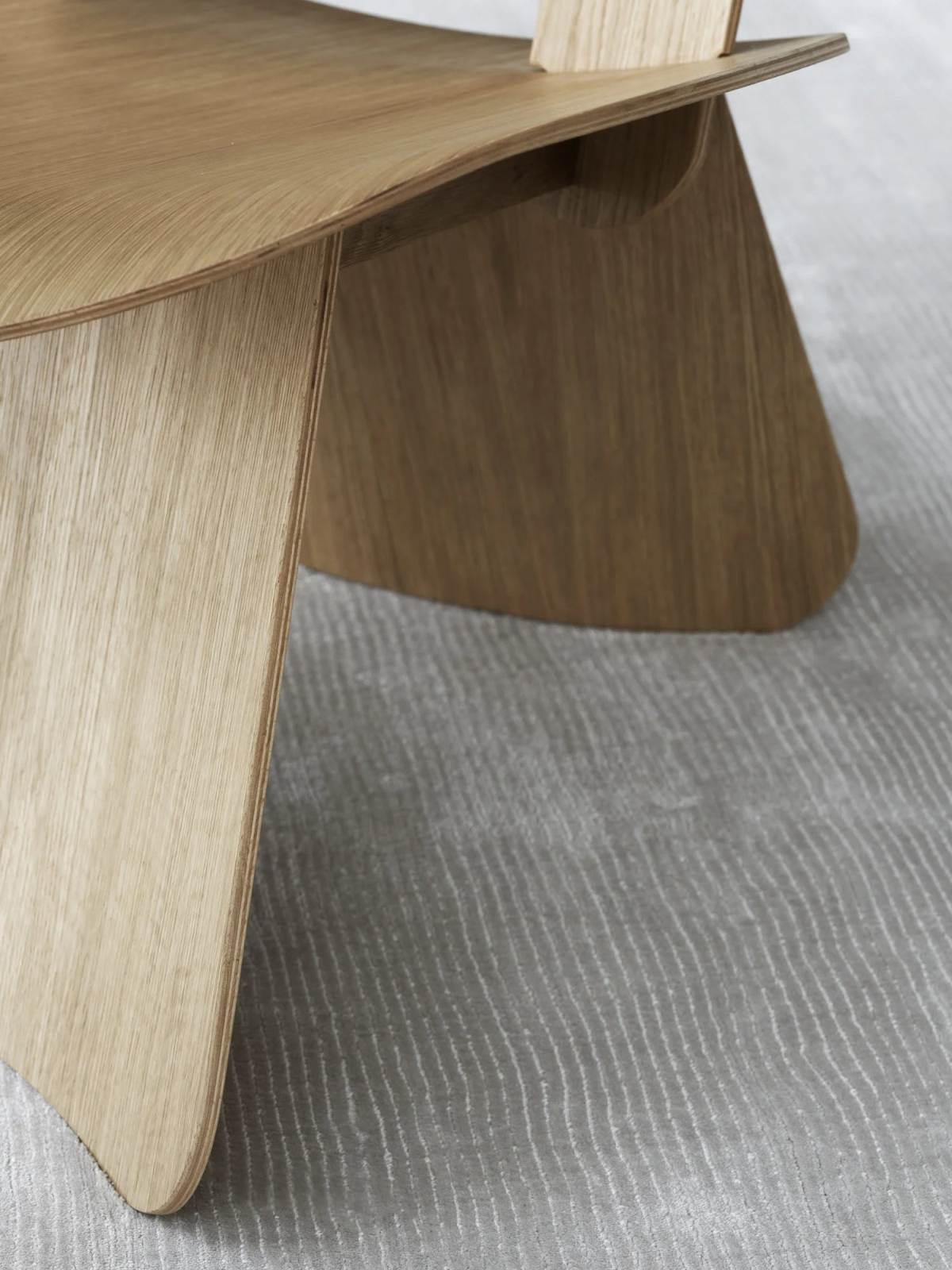 Detailaufnahme vom Blomus Nagomi Chair Stuhl aus hellem Holz auf einem grauen Teppich.