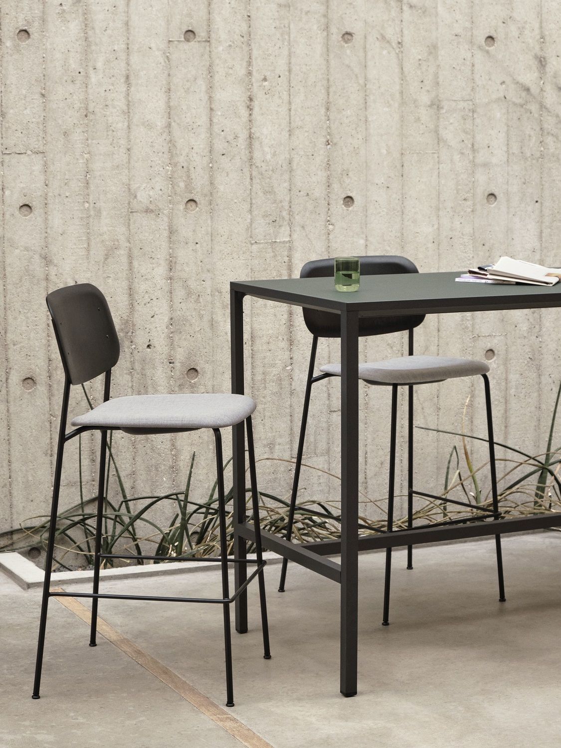Hay Soft Edge Barhocker in Grau und Schwarz an einem Tisch im Außenbereich.