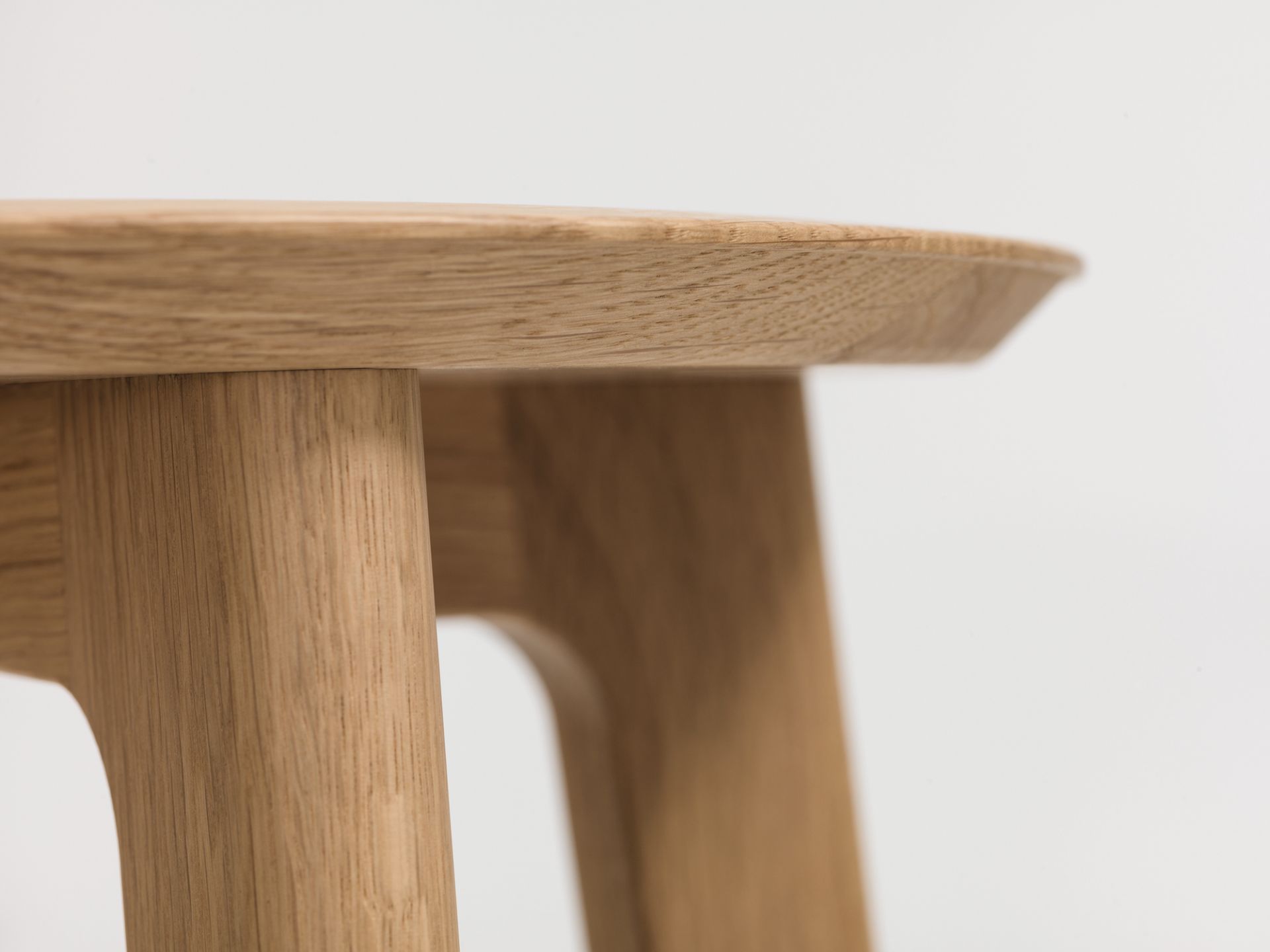 Detailaufnahme eines modernen Barhockers aus hellem Holz, Fokus auf Sitzfläche und Beine.