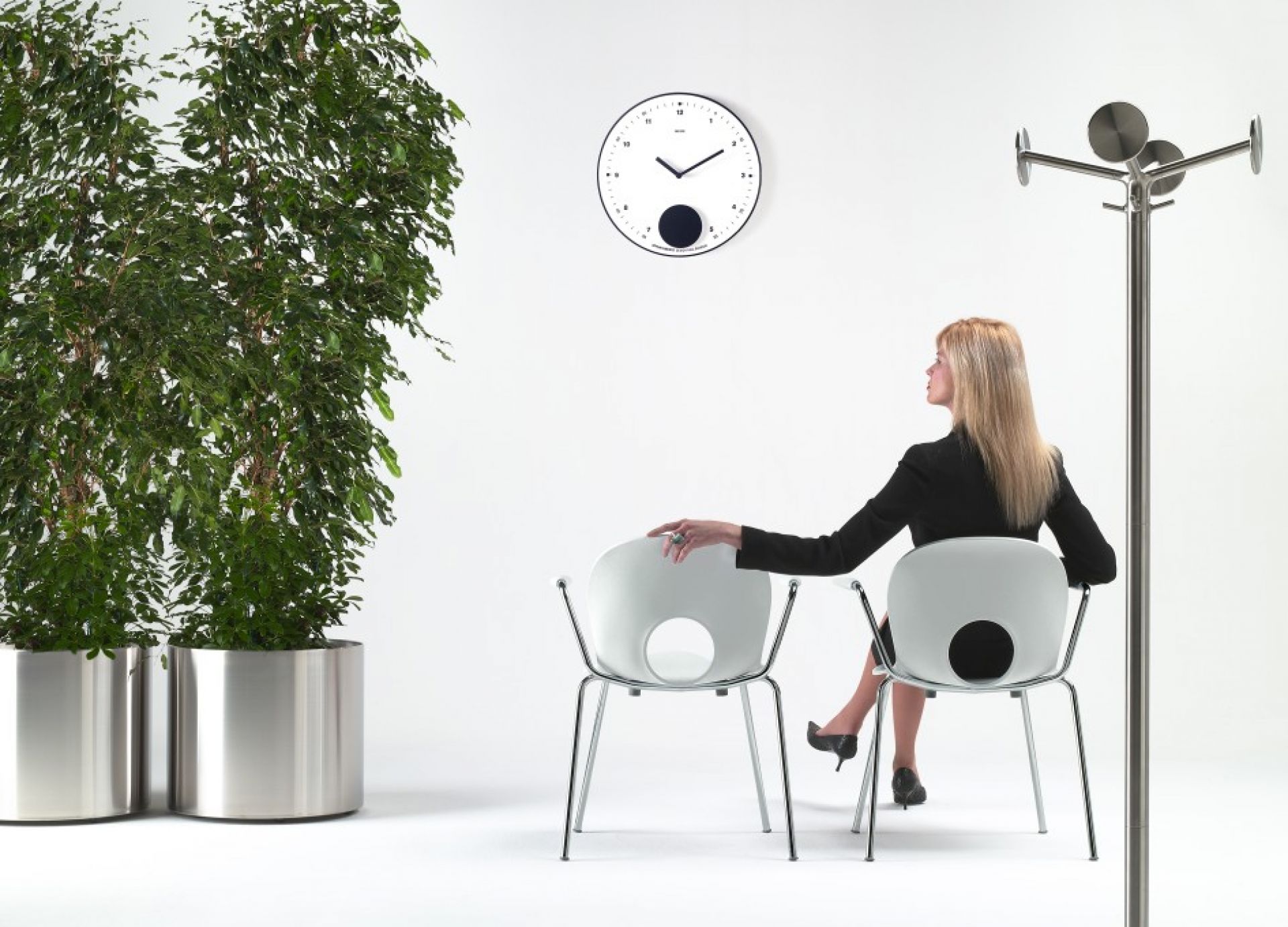 Nox Flora Blumentopf auf Rollen von Rexite neben Frau auf Stuhl, Zimmerpflanze im Metalltopf.