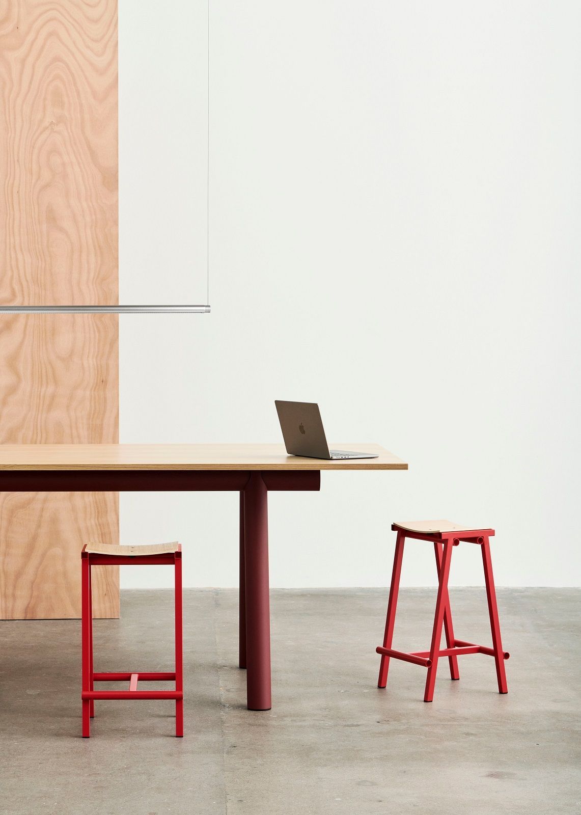 Hay Taburete 8 Barhocker in Rot neben Holztisch mit Laptop, minimalistisches Küchendesign.