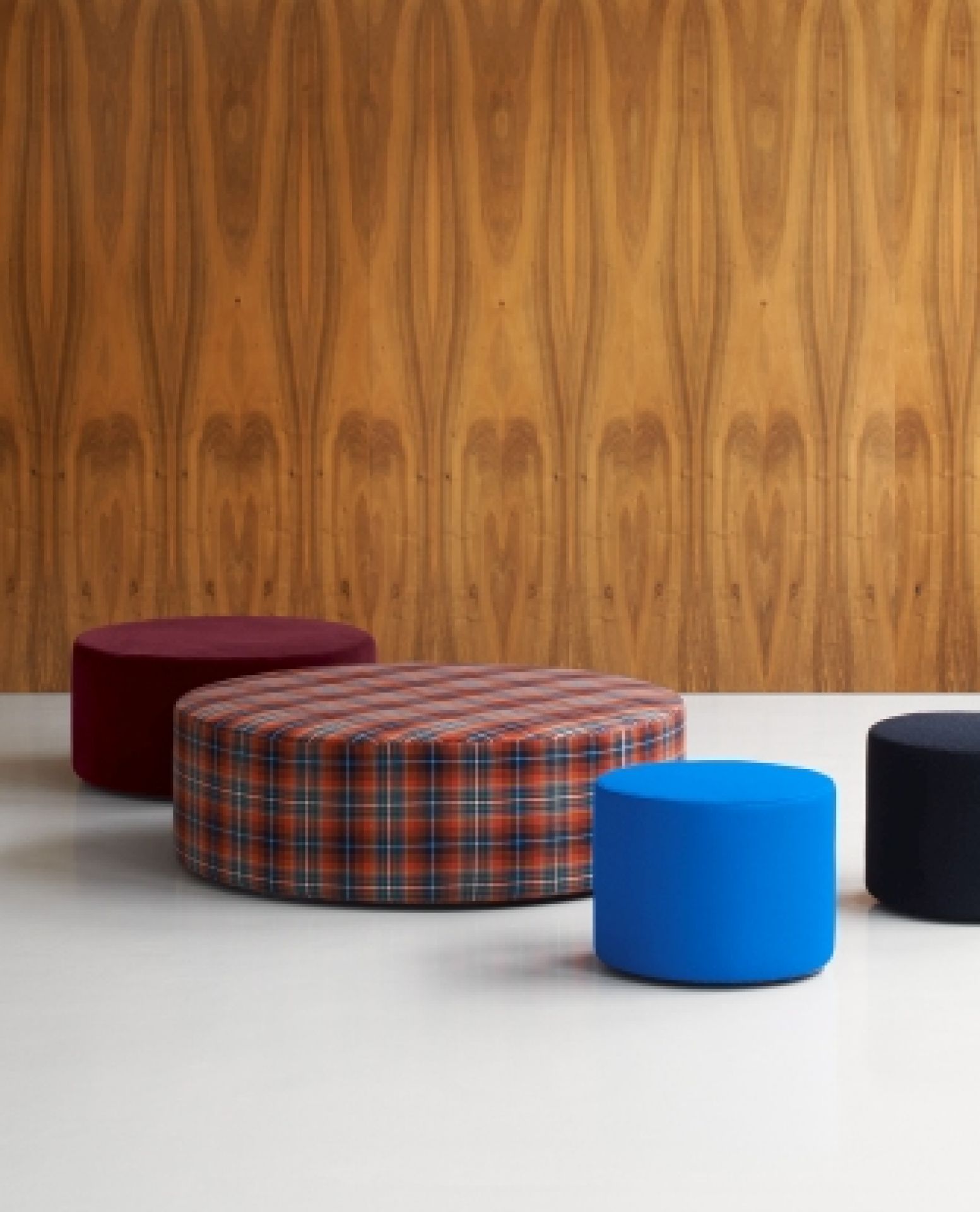 SF06 Kerman Modulsofa von e15: Runde, farbenfrohe Sitzmodule in Blau, Rot und Karomuster vor Holzwand.