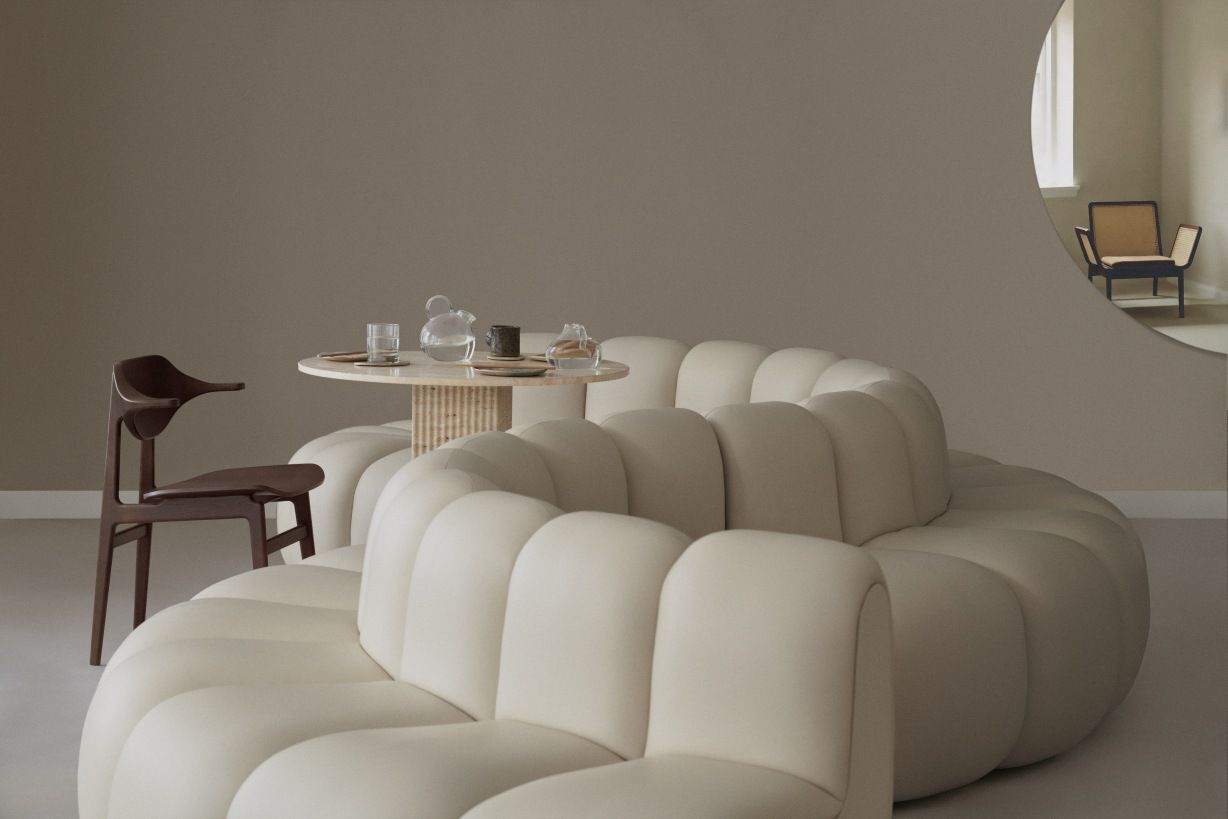 NORR11 Bufala Dining Chair aus Holz neben rundem Tisch und modularem Sofa in Beige.