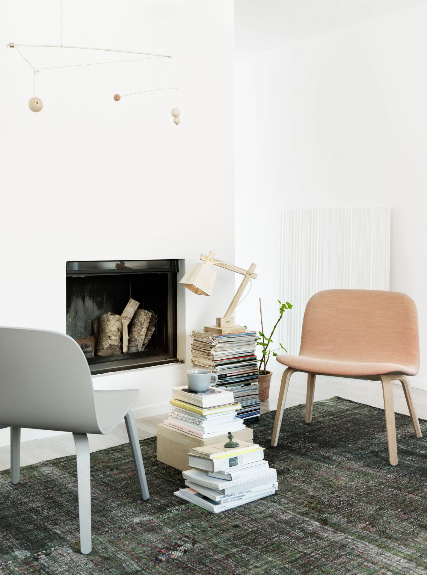 Heller Wohnraum mit Kamin, zwei Visu Lounge Chairs von Muuto und Bücherstapeln.
