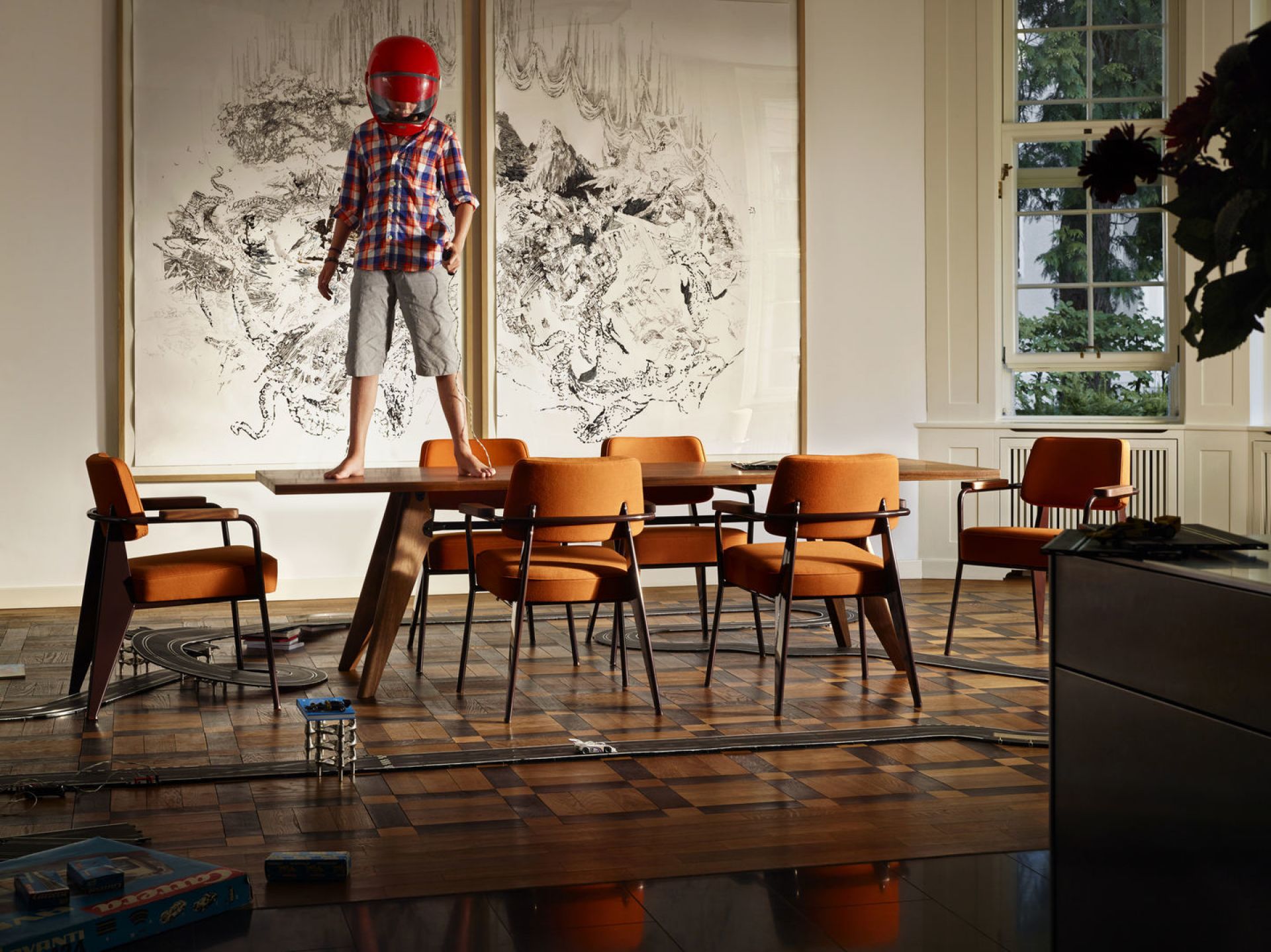 Orangefarbener Fauteuil Direction Sessel von Vitra in einem Wohnzimmer mit Kind auf dem Tisch.