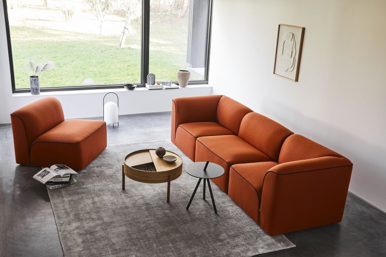 Grauer Tint Rug Teppich 90x140 cm von Woud unter orangefarbener Wohnzimmer-Couch und Beistelltischen.
