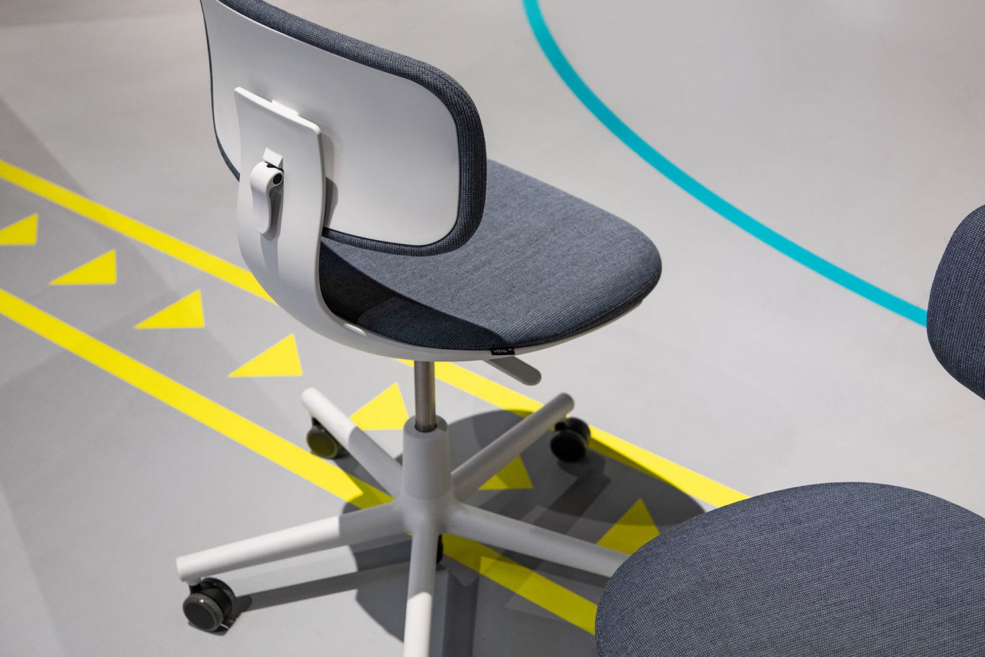 Nahaufnahme des Vitra Rookie Bürodrehstuhls mit grauem Stoffbezug und weißem Gestell, ideal für moderne Arbeitsplätze.