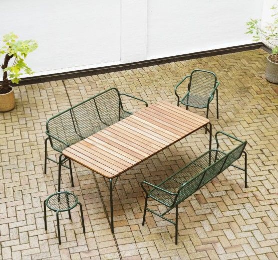Draufsicht: Normann Copenhagen Vig Stool Hocker, Teil einer grünen Outdoor-Sitzgruppe mit Holztisch auf Pflastersteinen.