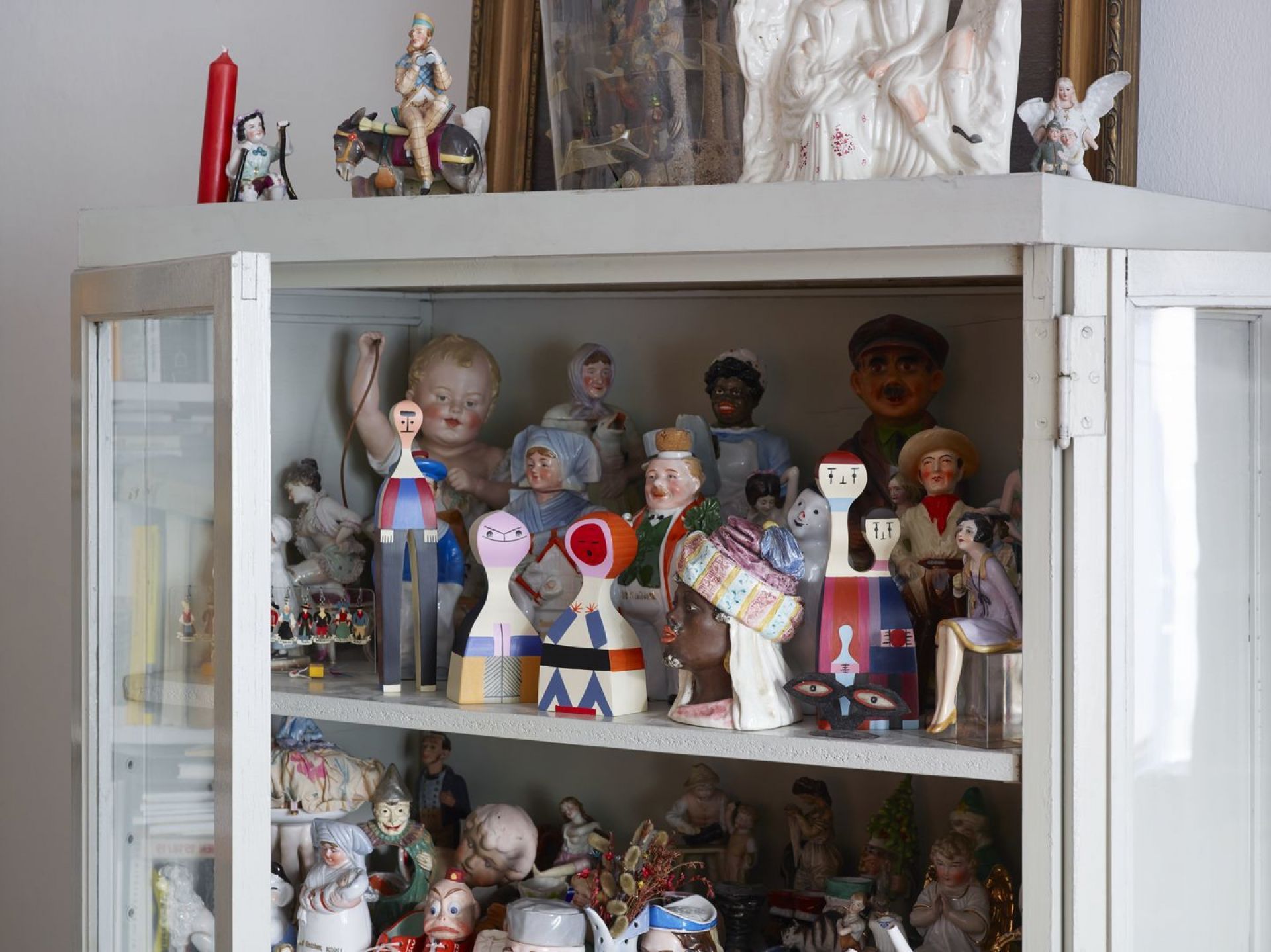 Regal mit Vintage-Puppen und Holzfiguren, darunter eine Vitra Wooden Doll, Sammlerstücke und dekorative Figuren.