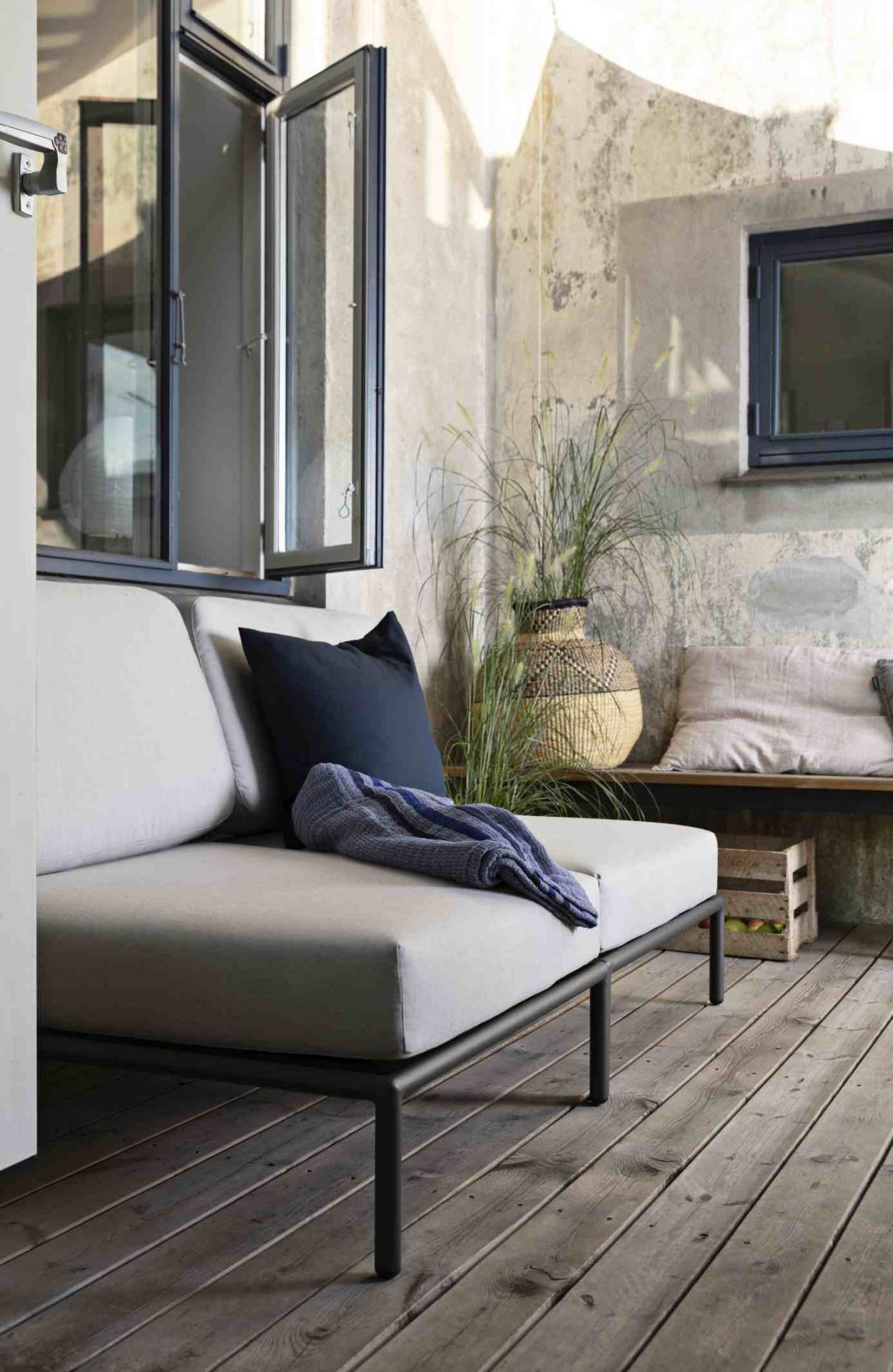 Houe Level Lounge Sessel für den Außenbereich mit Kissen und Decke auf Holzterrasse.
