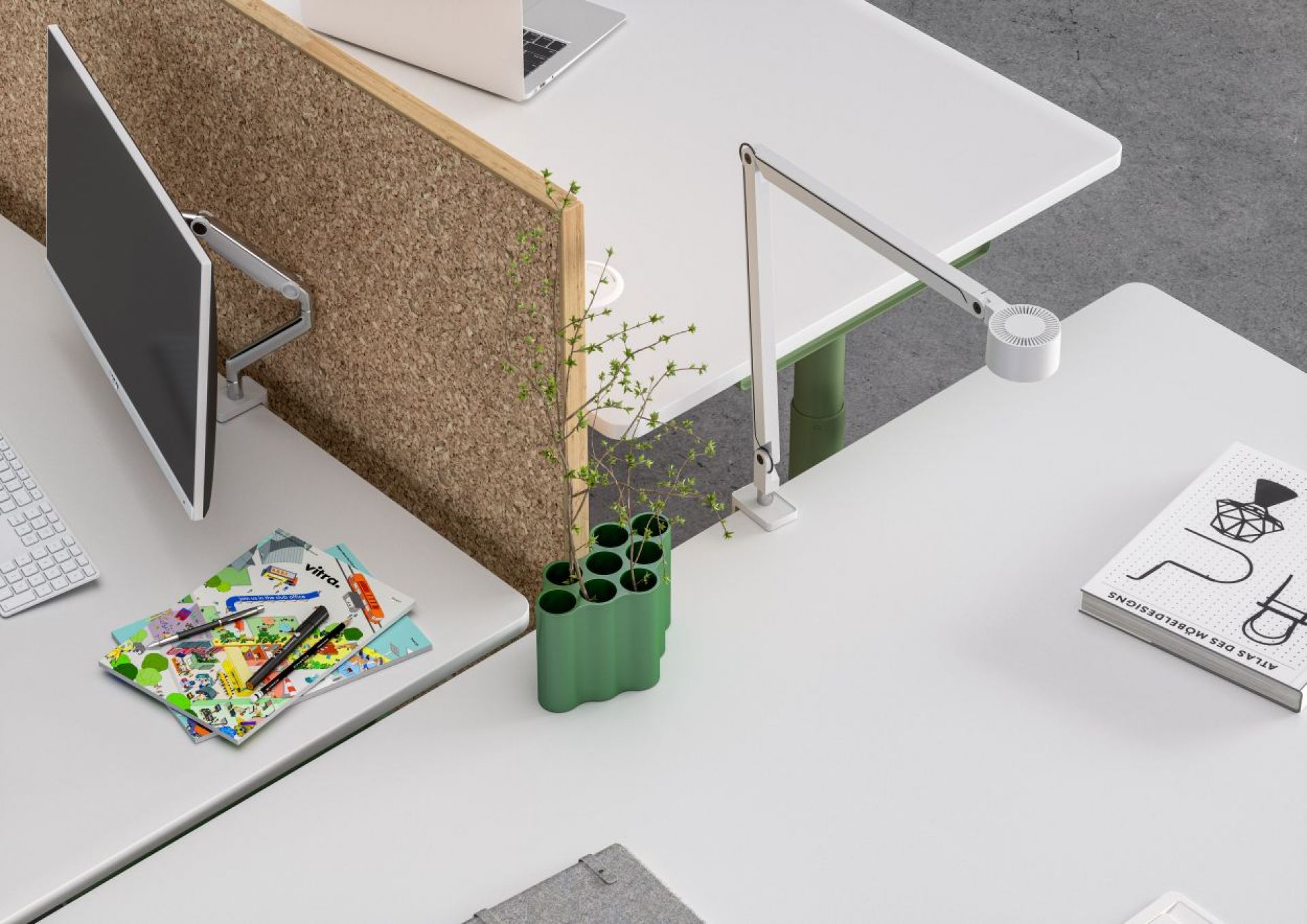 Detailaufnahme vom Vitra Tyde Steh- und Sitztisch mit Korkwand, Schreibtischlampe und Monitor für modernes Büro.