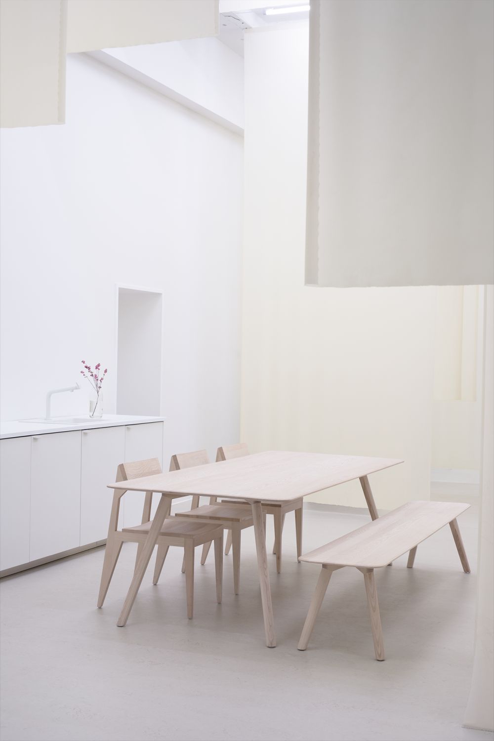 Helle MEYER Bank Large Out Essgruppe mit Holztisch, Stühlen und Bank in minimalistischem, weißem Raum.