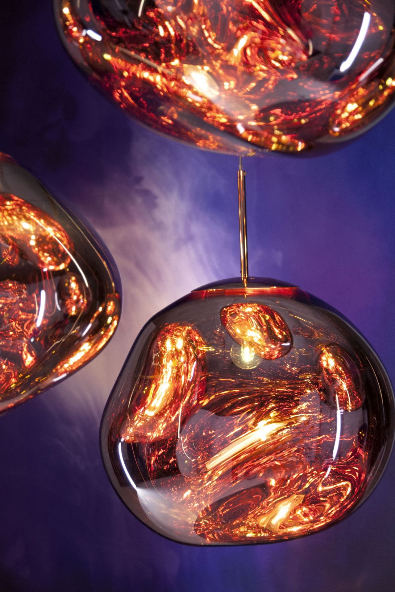 Nahaufnahme von drei Tom Dixon Melt LED Hängeleuchten in Kupfer mit warmem Lichtschein.