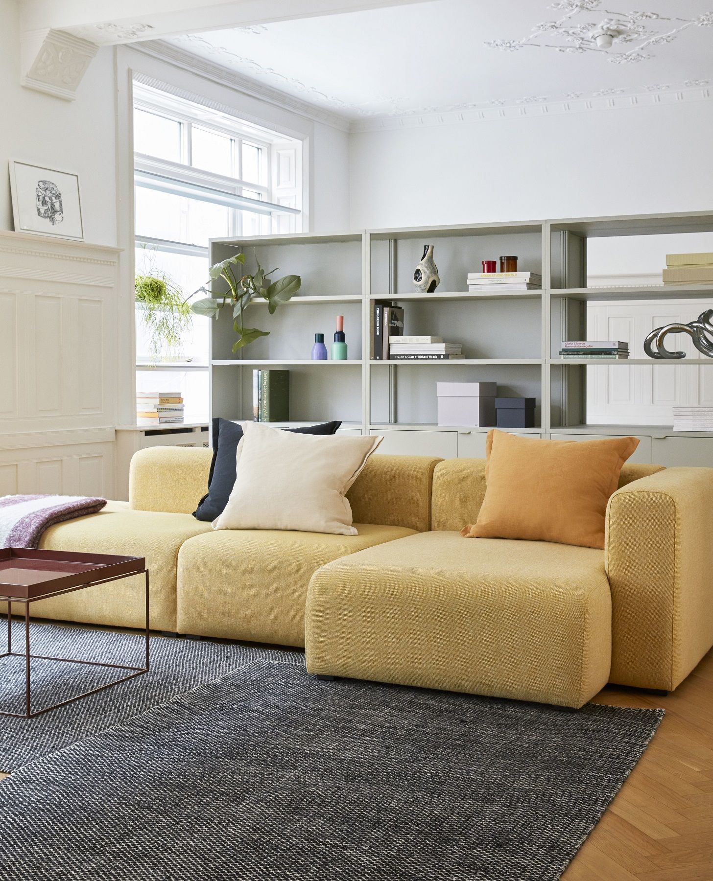 Wohnzimmer mit gelbem Sofa, Couchtisch und Hay New Order Sideboard Wandregal in hellgrau.
