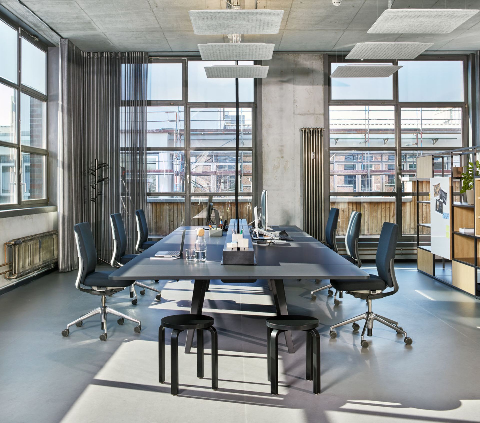 Büroraum mit langem Tisch und mehreren Vitra ID Chair Bürodrehstühlen in Grau.