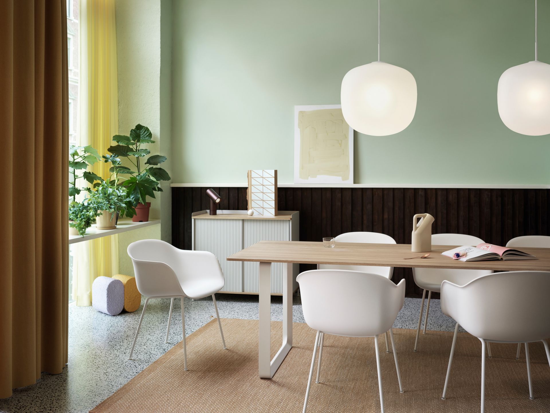 Esszimmer mit Esstisch, weißen Stühlen und zwei grauen Rime Pendelleuchten von Muuto über dem Tisch.