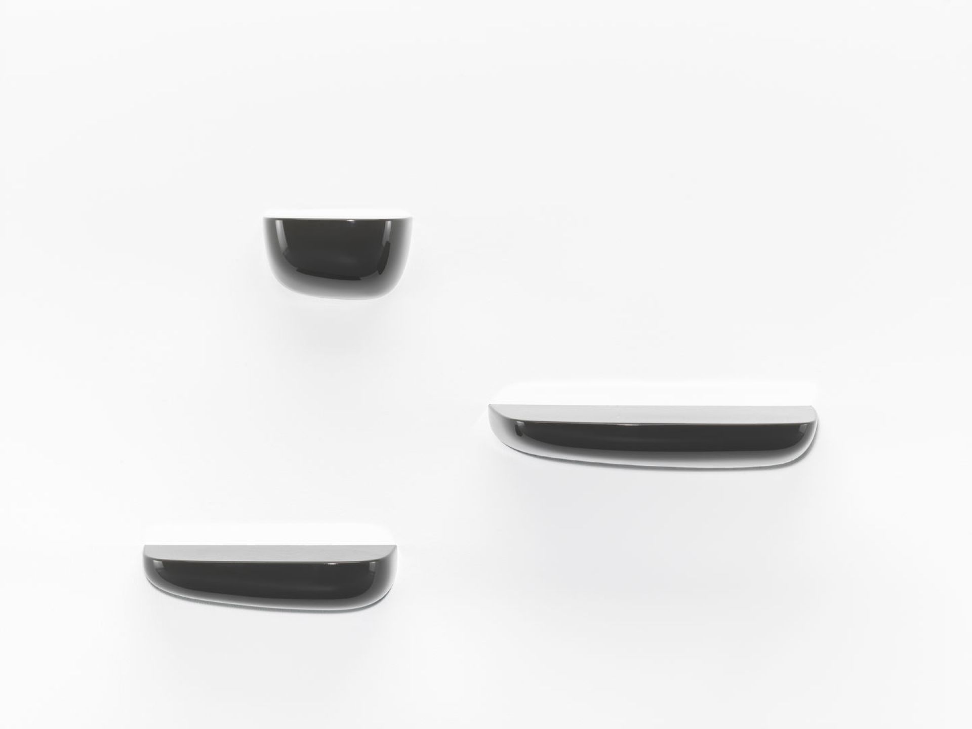 Drei schwarze Vitra Corniches Wandboards in verschiedenen Größen an einer weißen Wand.