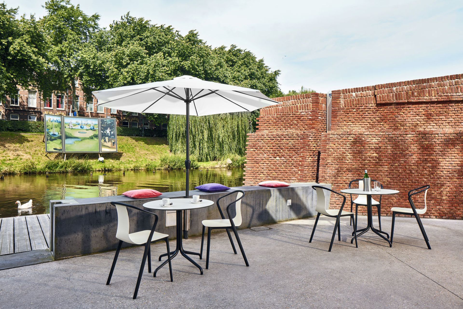 Draufsicht auf Belleville Armchair Plastic Stühle von Vitra an Tischen im Außenbereich mit Flussblick.