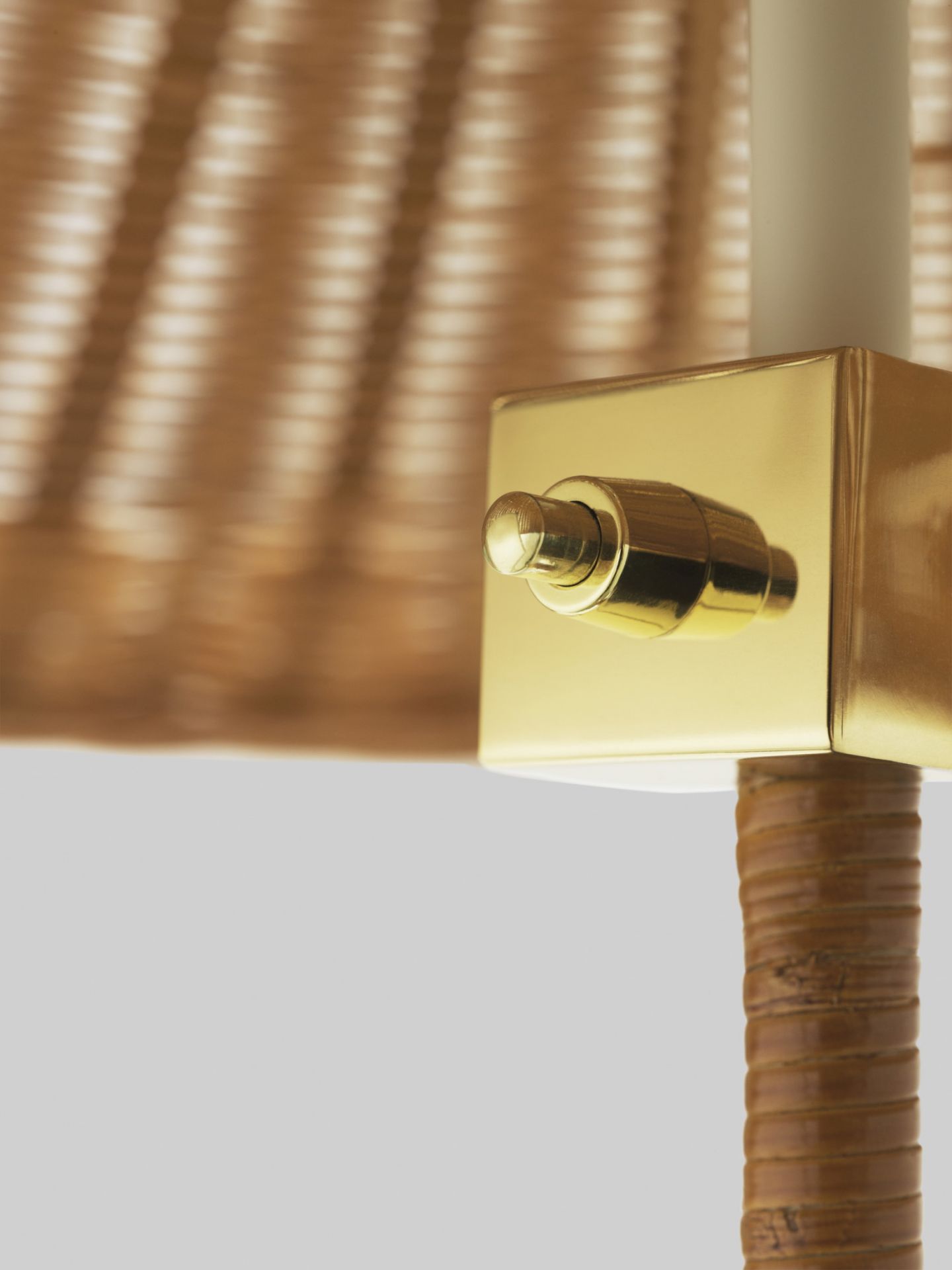 Detailaufnahme der Gubi 9602 Stehleuchte: Goldener Schalter und Lampenschirm aus Rattan. Design Stehleuchte.