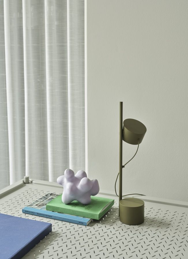 Detailaufnahme vom Muuto Flow Coffee Table, einem Couchtisch auf Rollen, mit Lampe und Deko-Objekt.