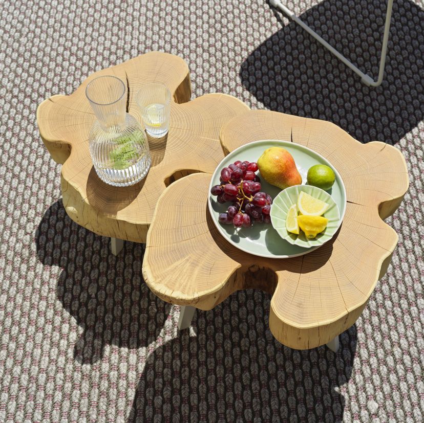 BC 05 Stomp Outdoor Couchtisch aus Holz mit Getränken und Obst auf einem Teppich.