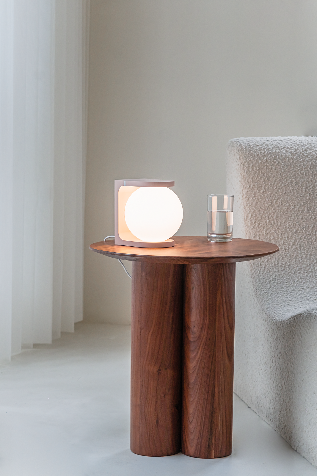 Nahaufnahme der Plat Reading Lamp Tischleuchte von house of home auf einem Holztisch mit Wasserglas.