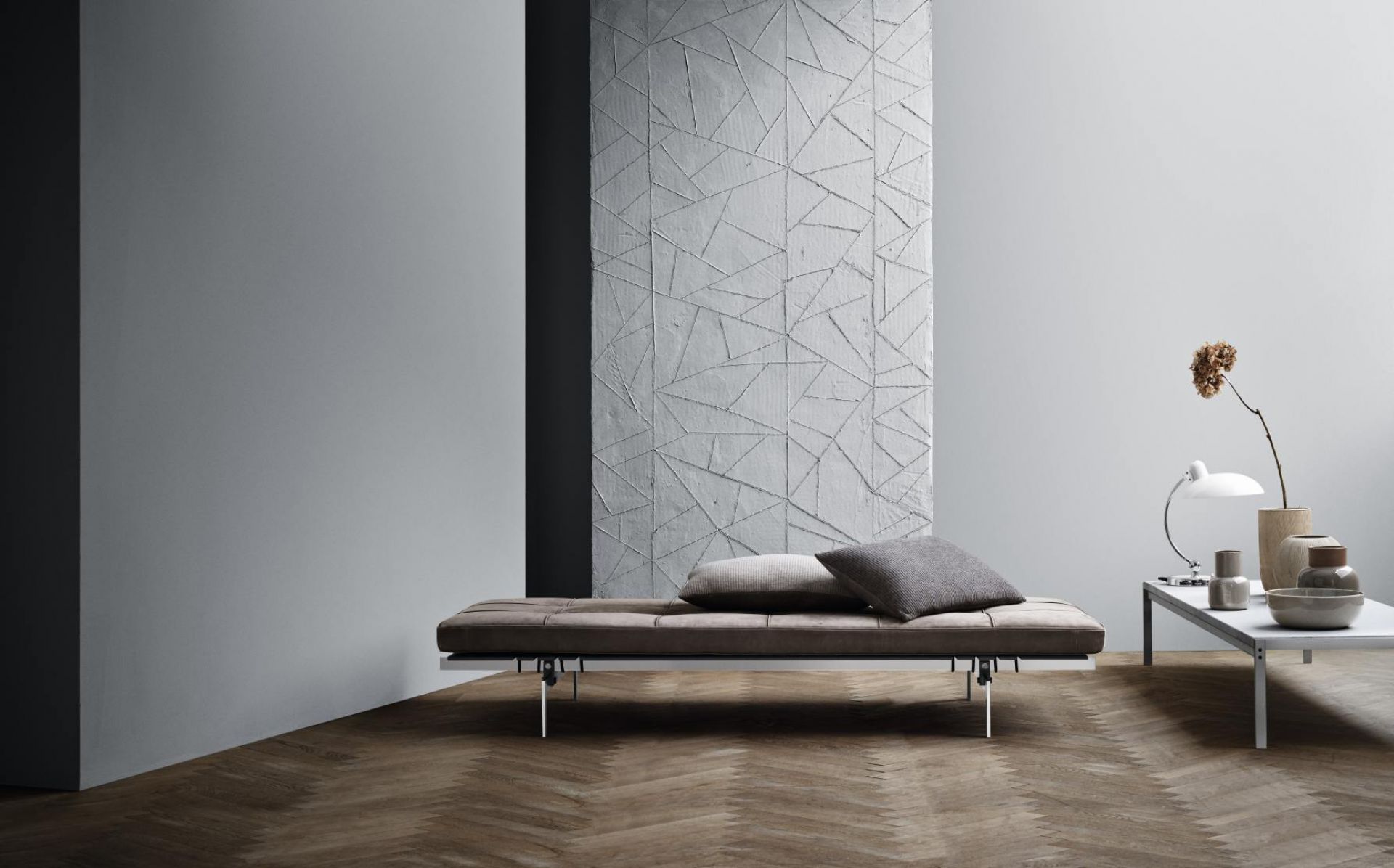 Elegante PK80 Liege von Fritz Hansen mit braunem Lederbezug und zwei Kissen im modernen Wohnzimmer.