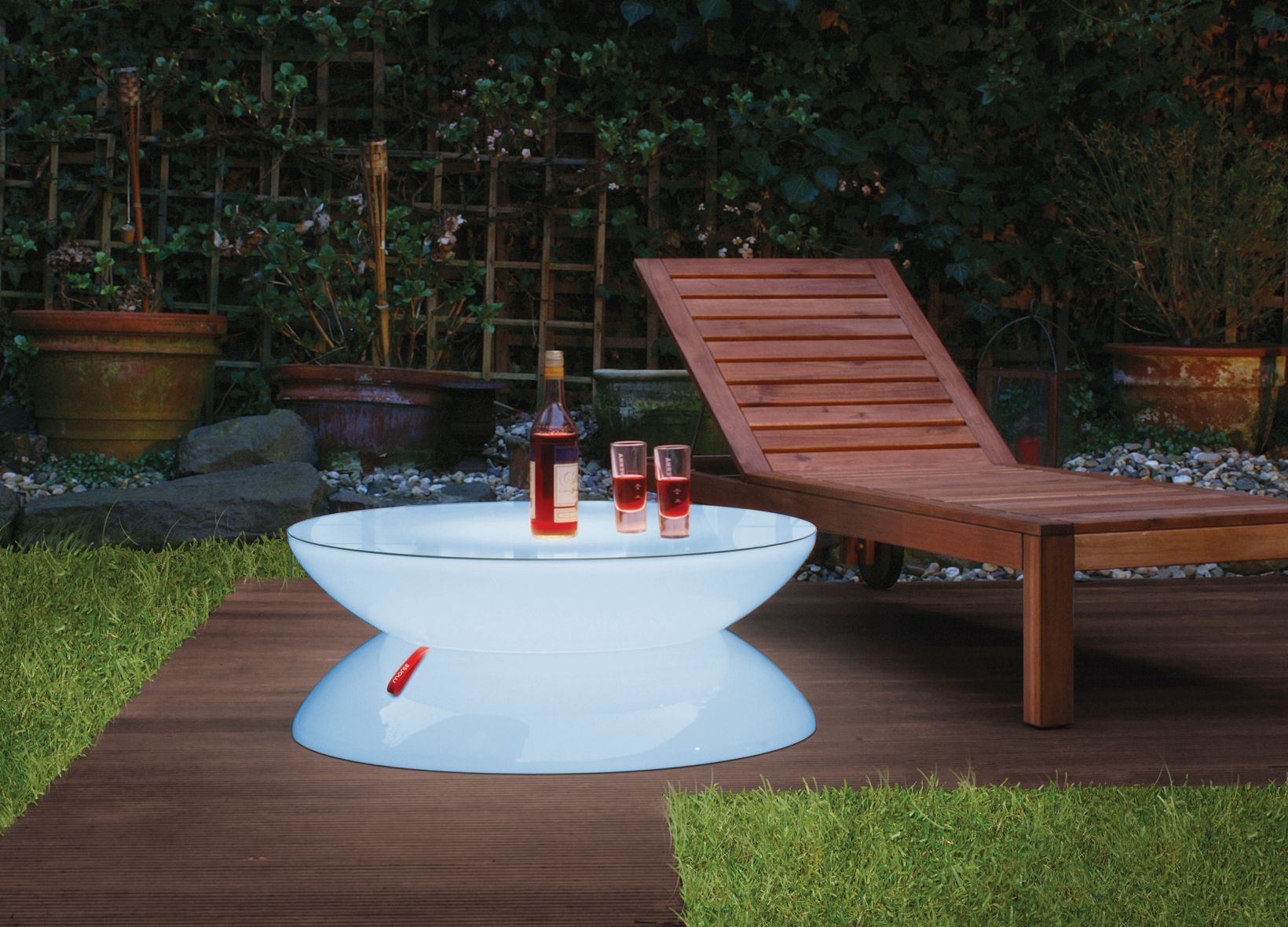 Moree LED Lounge Tisch mit Getränken und Liege im Garten.