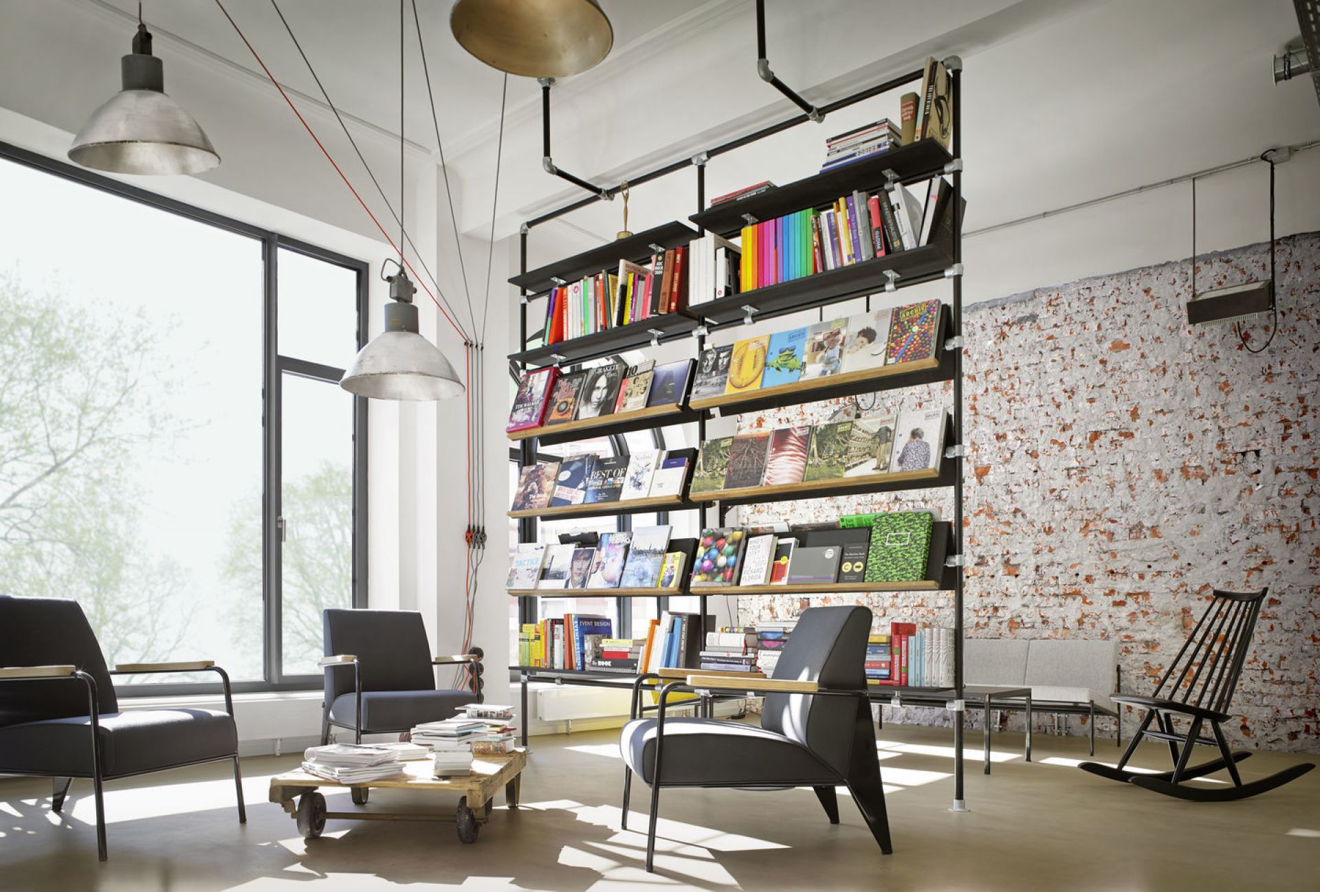 Innenaufnahme mit drei Fauteuil De Salon Sesseln von Vitra, Bücherregal und Loft-Atmosphäre.