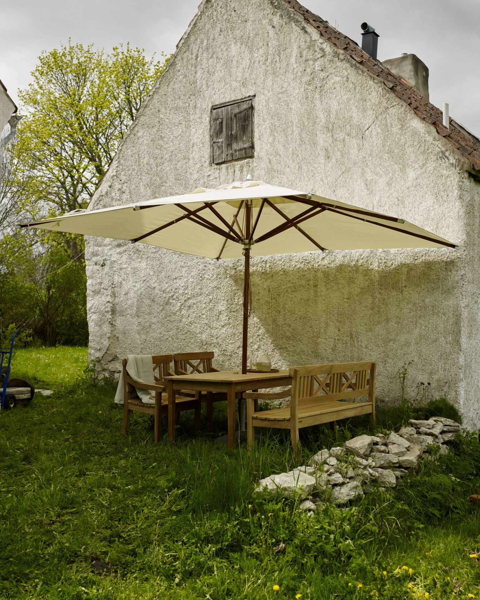 Drachmann Bank von Skagerak by Fritz Hansen im Garten mit Tisch und Sonnenschirm.