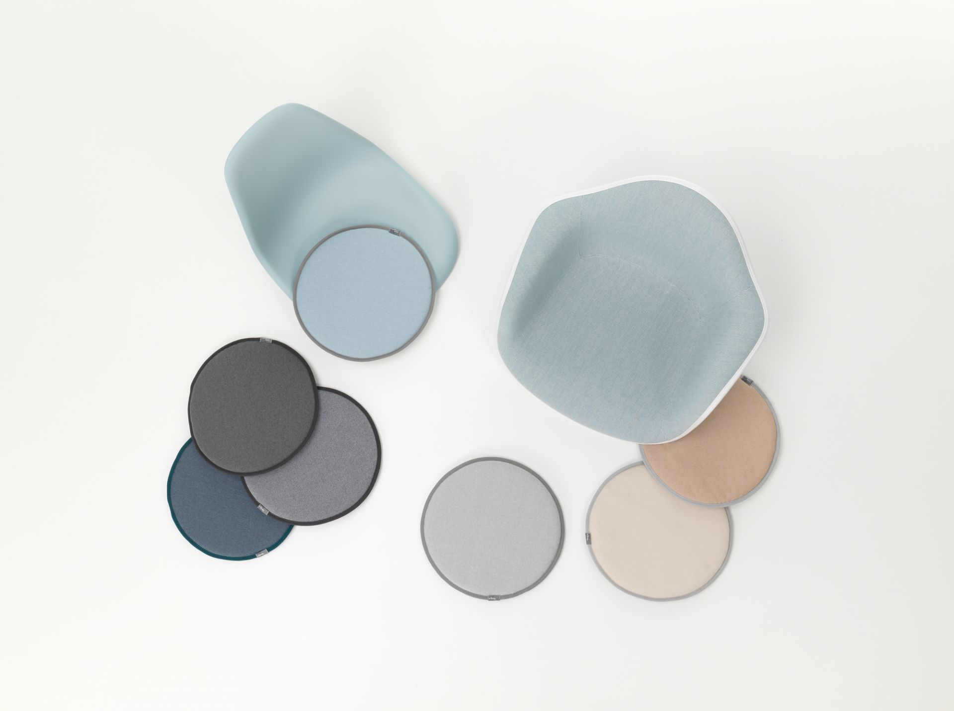 Vitra Seat Dot Sitzkissen in Grün- und Cognactönen, runde Form, Textur und Stühle im Hintergrund.