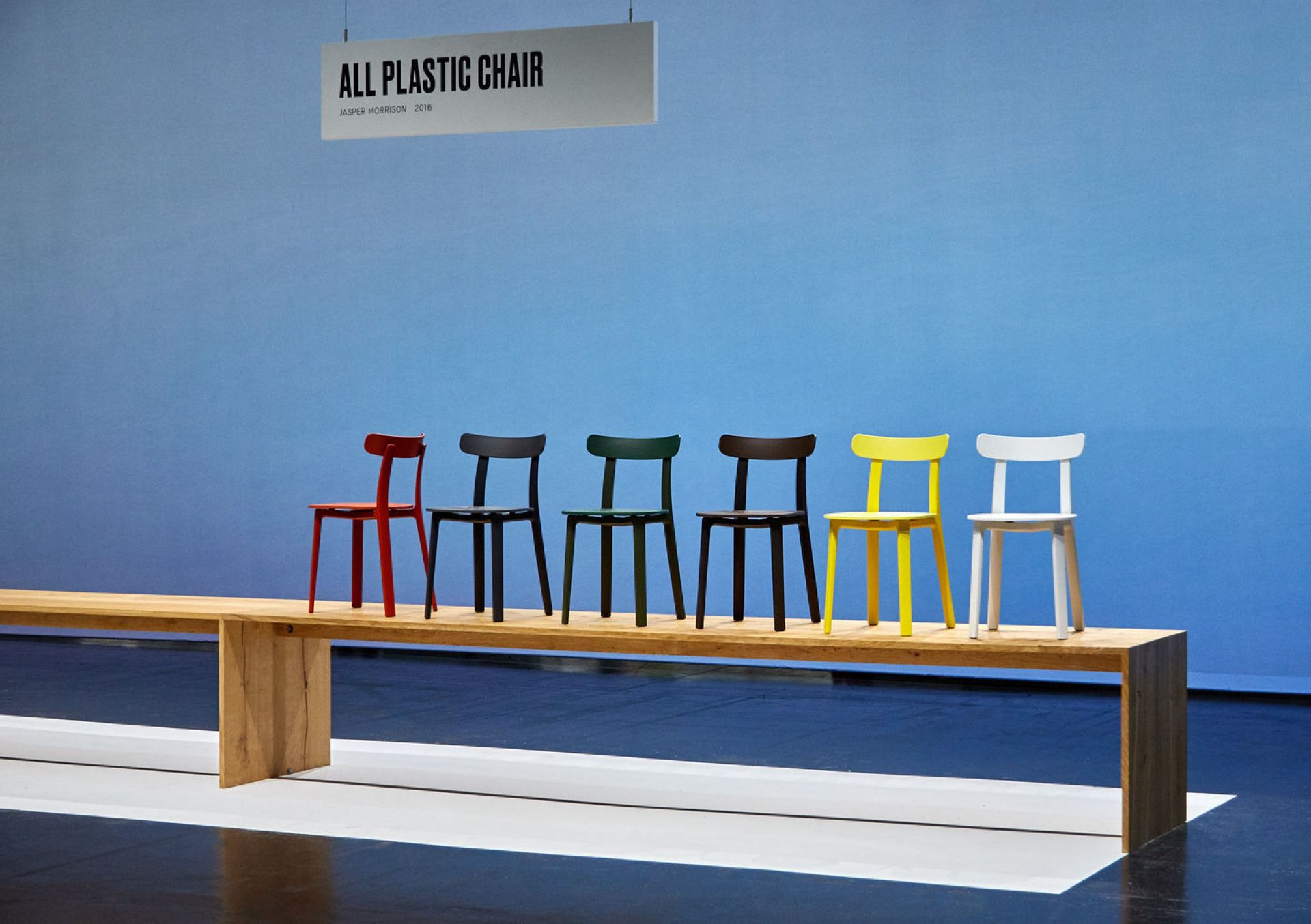 Vitra All Plastic Chair Outdoor Stühle in verschiedenen Farben auf einer Holzbank.
