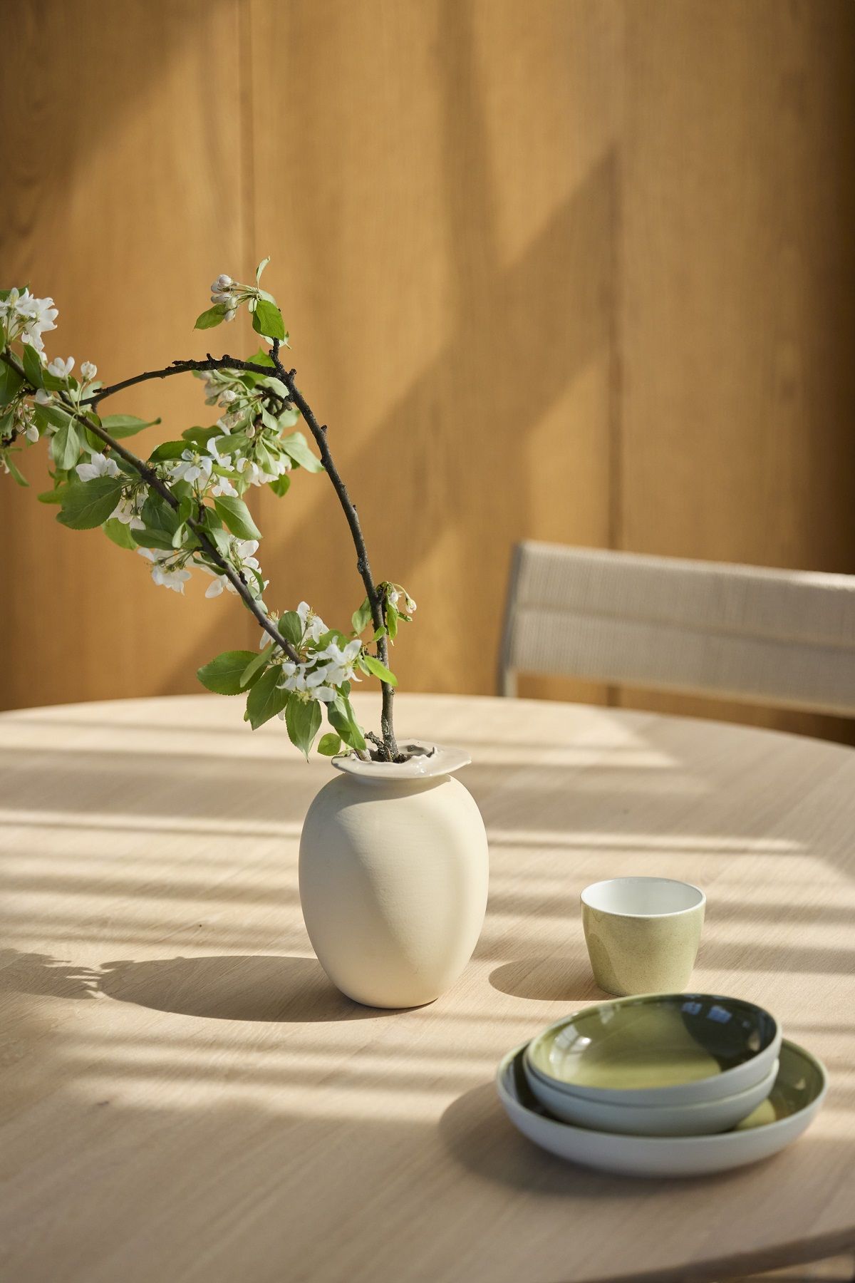 Detailaufnahme des Northern Expand Esstisch Circular mit Geschirr und Blumenvase im warmen Licht.