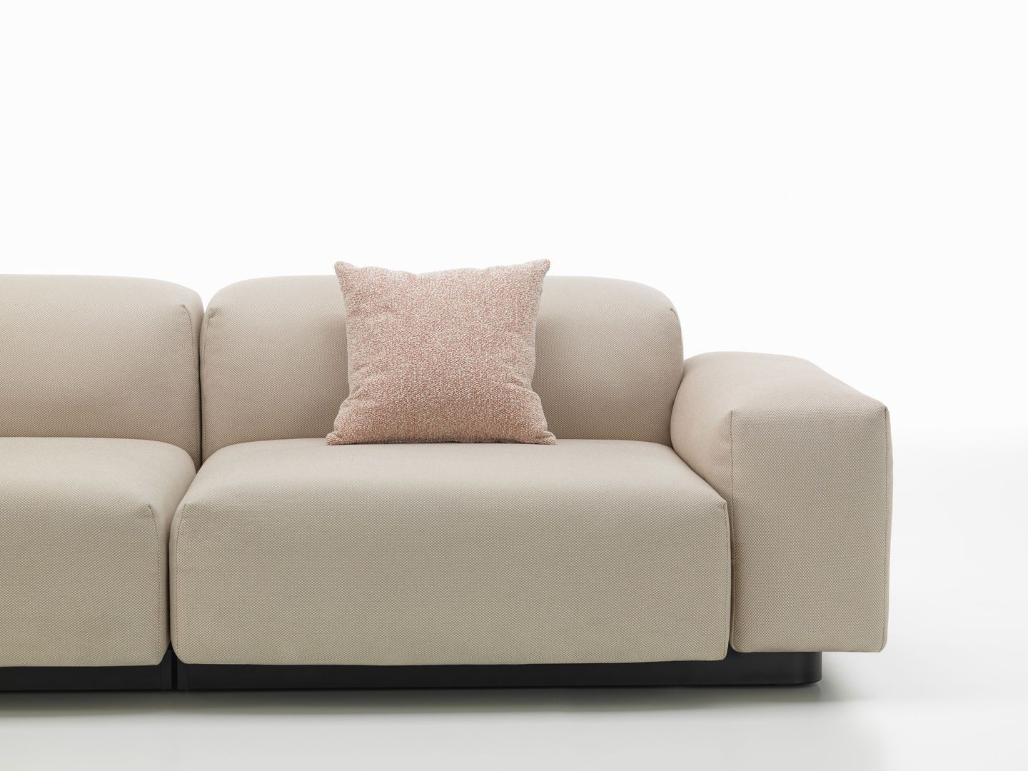 Beiges Sofa mit einem rosa-weiß gemusterten Vitra Cushions Kissen, modernes Wohnzimmer-Interieur für gemütliches Ambiente.