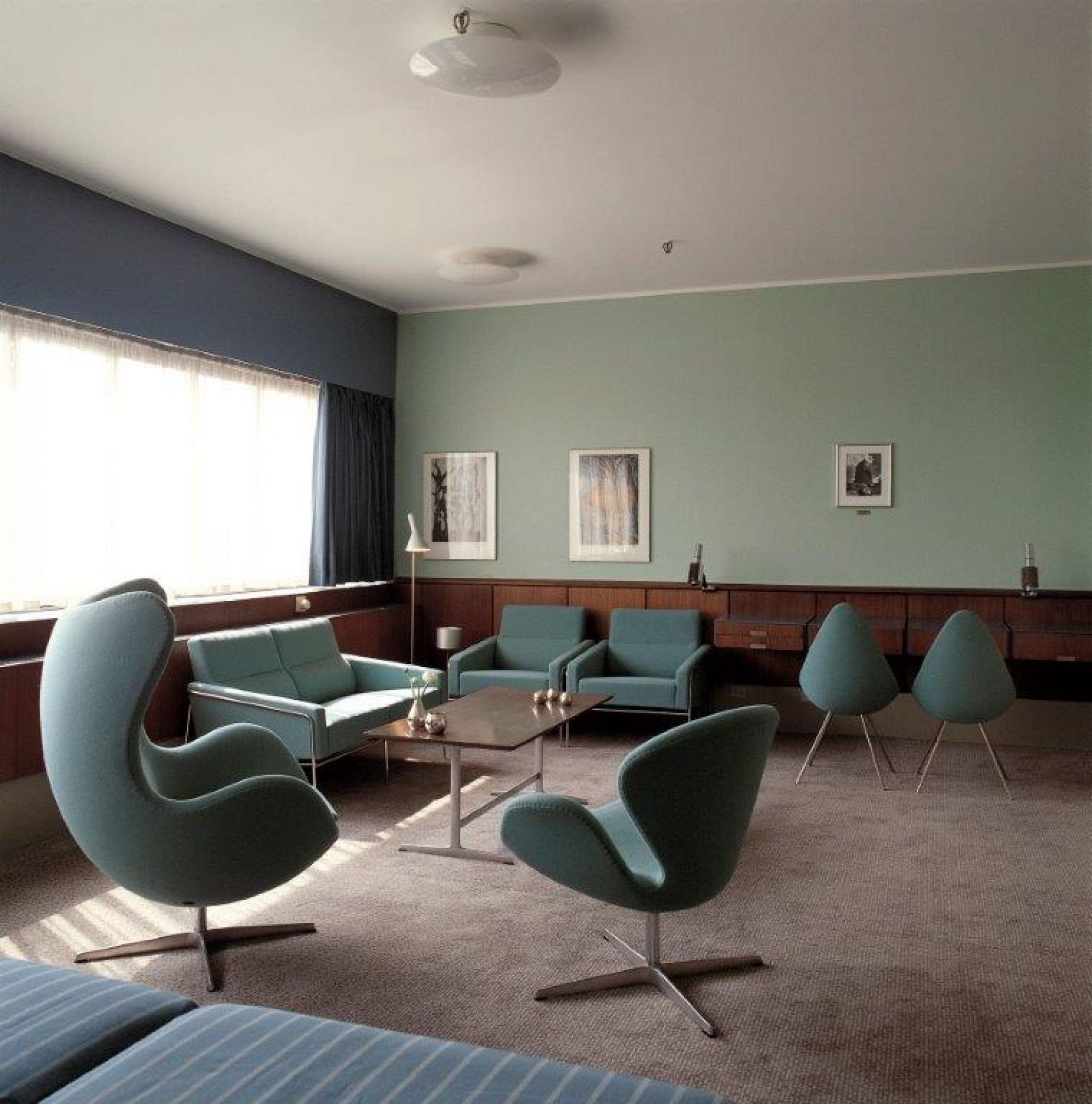 Innenaufnahme mit blaugrünen Egg Chairs und passenden Sofas von Fritz Hansen in einem stilvollen Wohnzimmer.