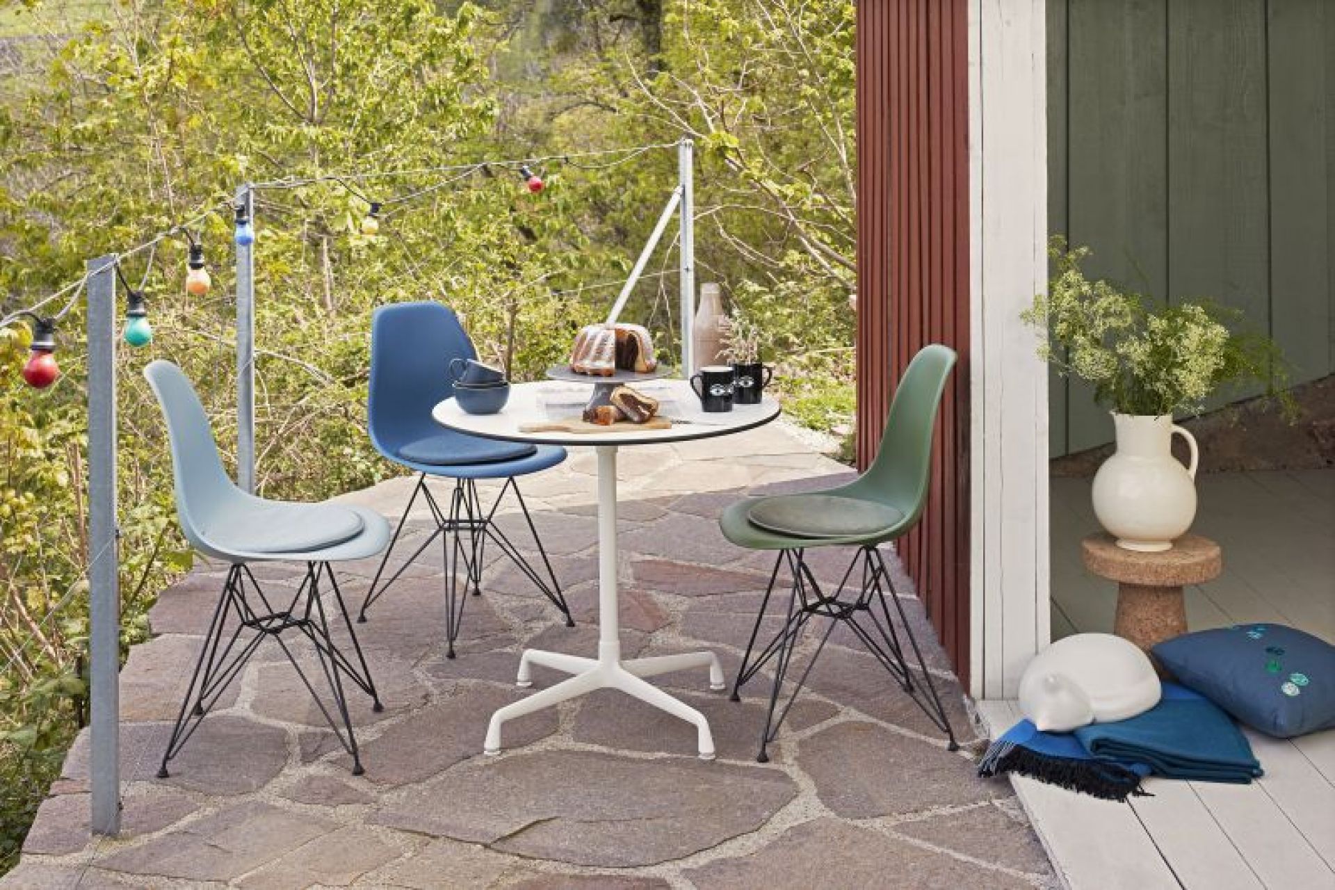 Vitra Eames Contract Table runder Tisch mit Stühlen im Außenbereich, ideal für Garten und Terrasse.